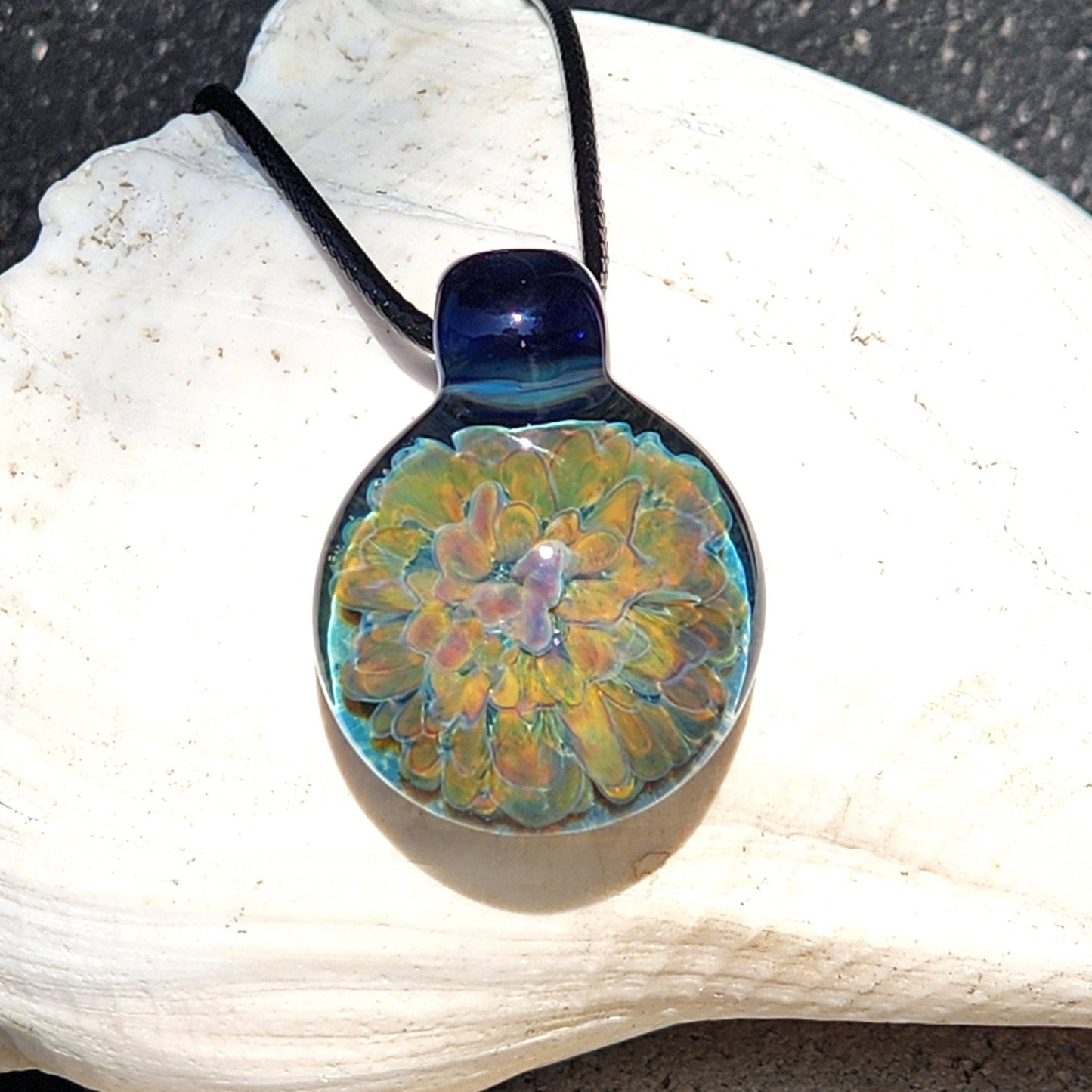 Glass pendant necklace with a multicolor trippy flower design, handmade with a glossy finish and black adjustable cord.