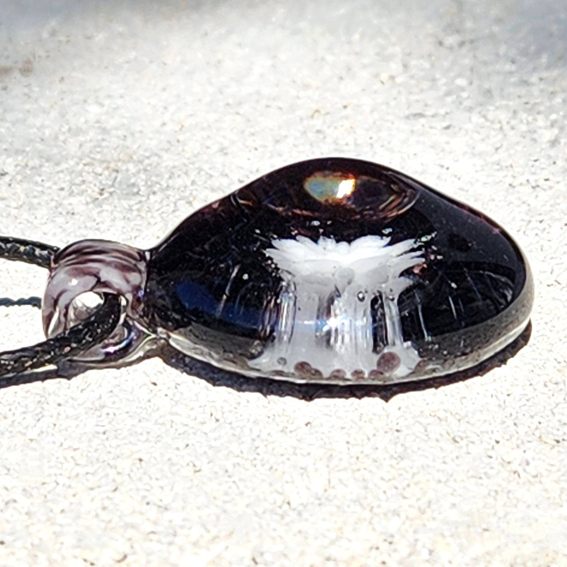 Close-up side angle of Heady Blown Glass Pendant showing depth and clarity of white floral design in black glass, handmade in the USA.