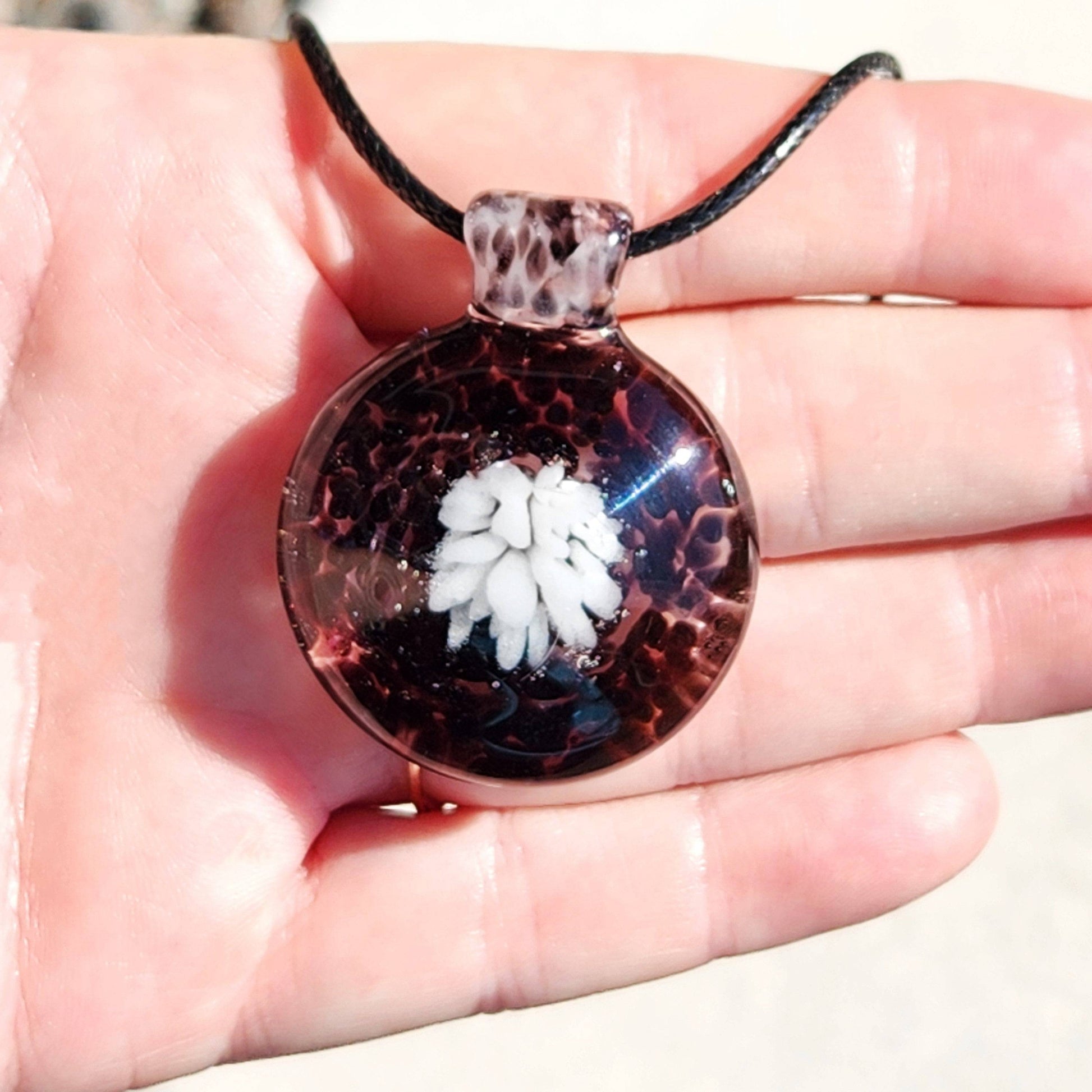 Handmade White and Black Glass Necklace shown in palm, emphasizing floral design and crushed glass texture in unique pendant jewelry.