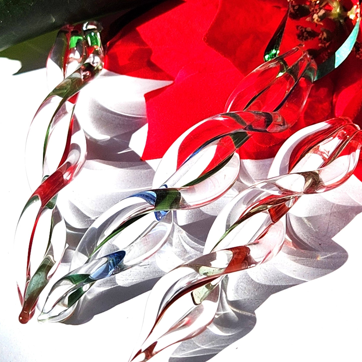 Close-up of custom handblown glass icicle ornaments in red and green, showcasing intricate craftsmanship for festive holiday decorating.