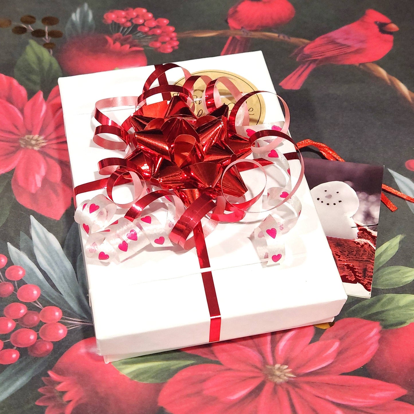 Gift-wrapped box with red and white ribbon and holiday-themed card. Perfect packaging for handmade blue and white Christmas ornaments.