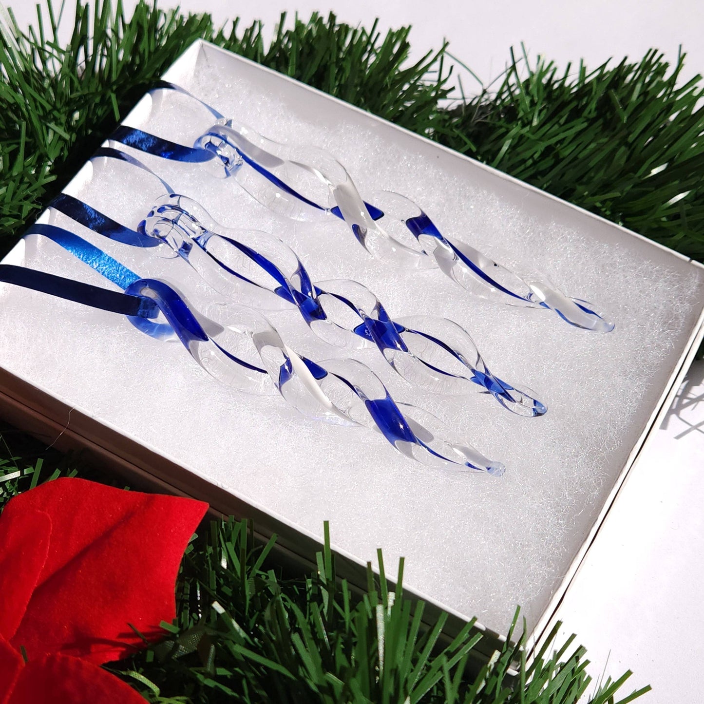 Close-up of handmade blue and white glass icicle ornaments in a gift box, perfect for holiday tree decor or seasonal home accents.