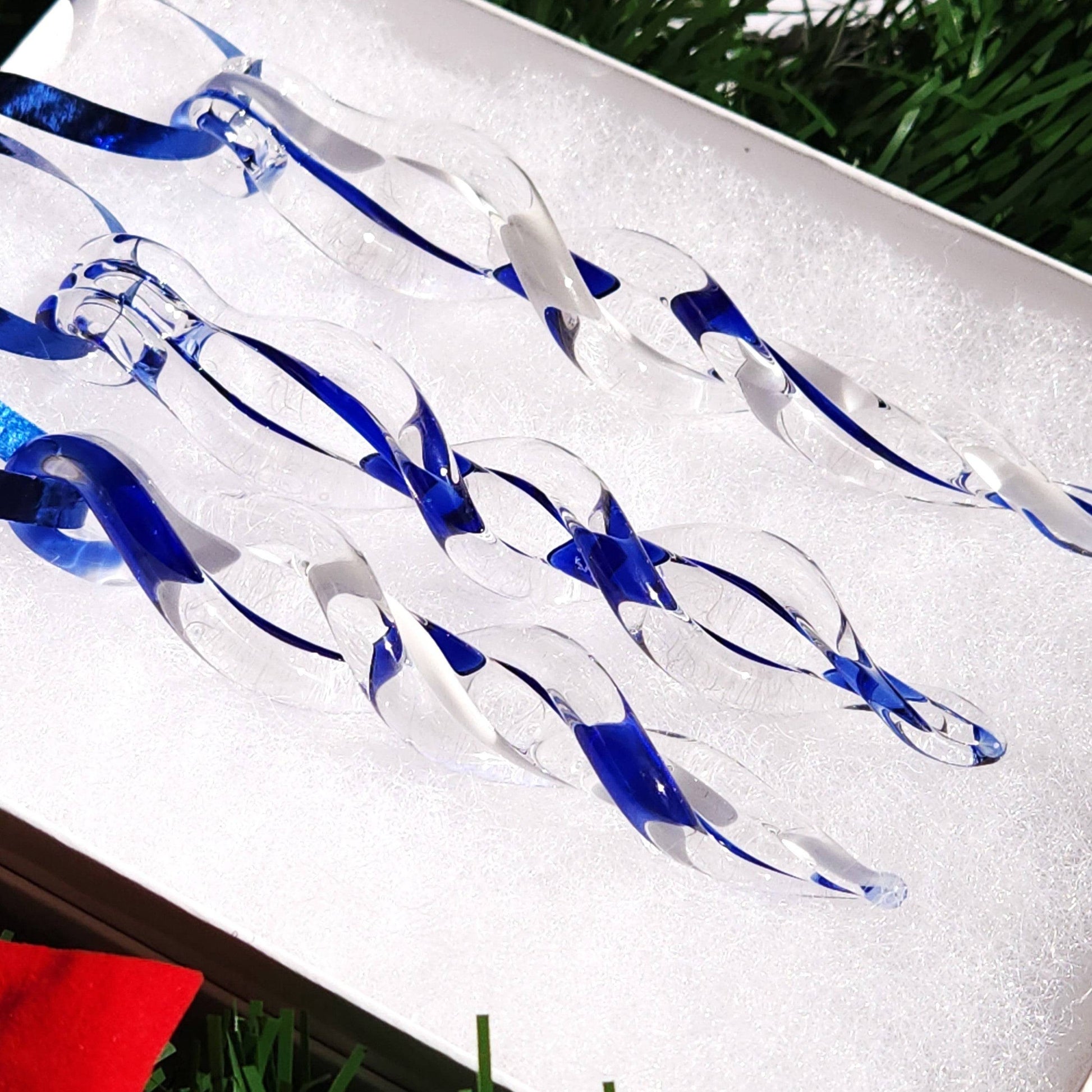 Set of 3 blue and white glass icicle ornaments resting in a white box, highlighting their elegant twist design for holiday decorating.