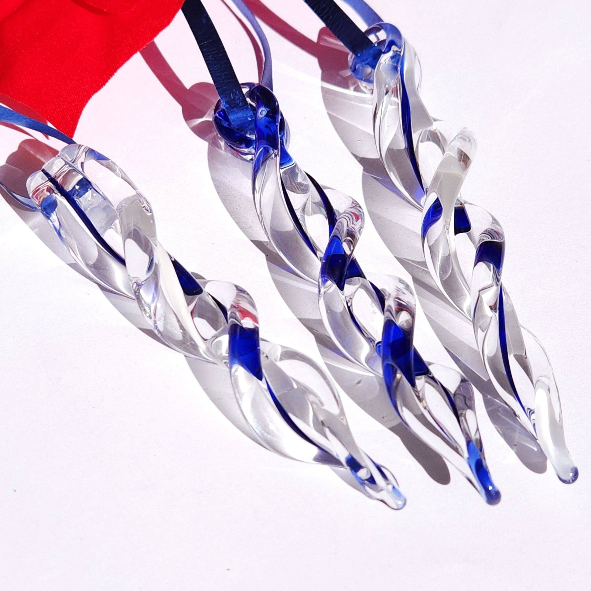 Three blue and white twisted glass icicle ornaments hanging together, ideal for enhancing Christmas tree or winter-themed decor.
