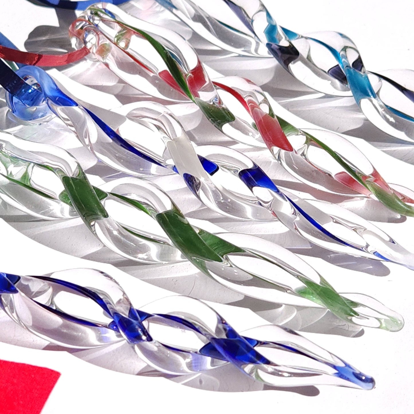 Close-up of assorted handmade glass icicles in red, green, and blue, highlighting the unique twisted design for holiday decor.