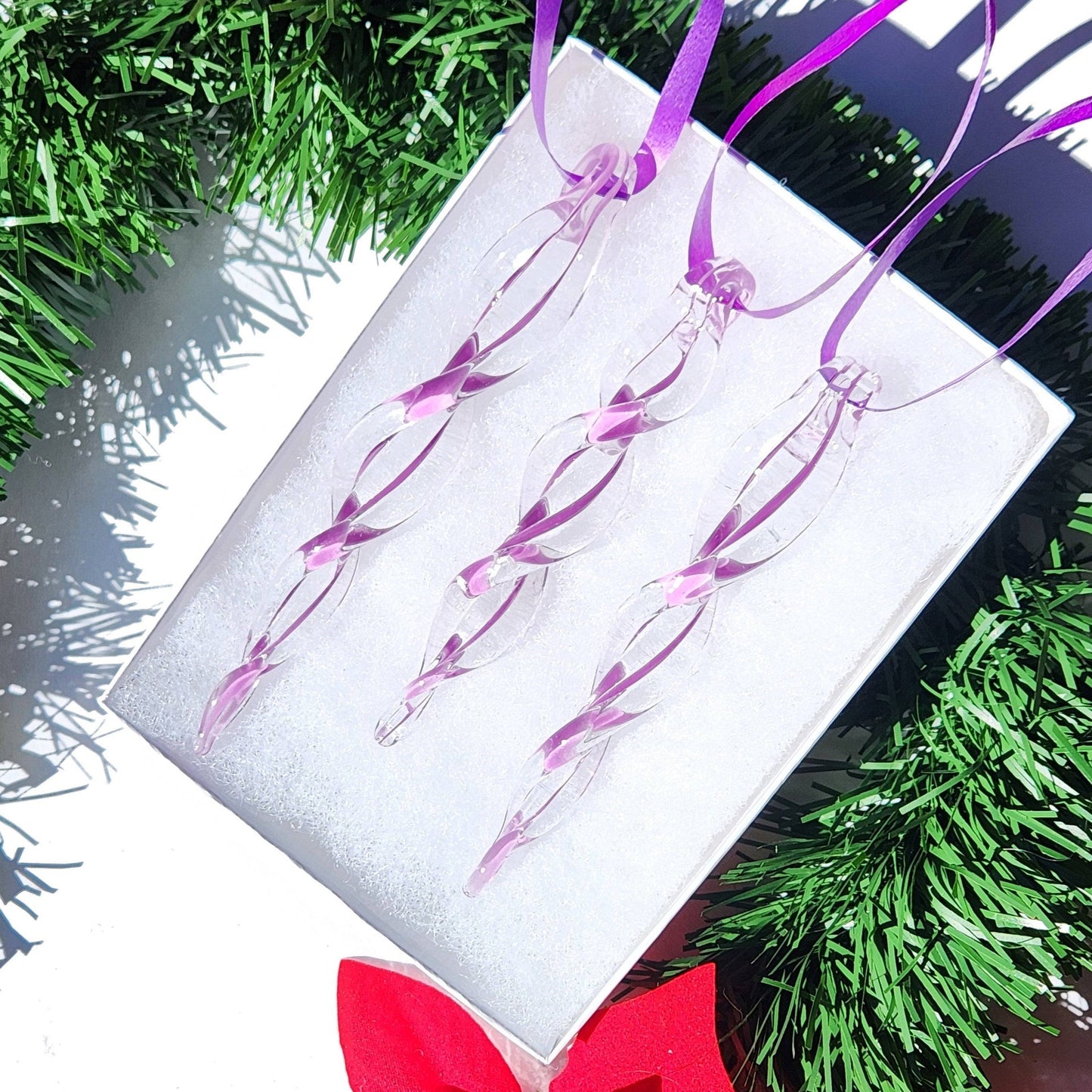 Box of three purple handmade glass icicle ornaments with ribbon loops, ideal for elegant Christmas tree decoration or gifting.
