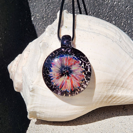 Handmade jewelry blown glass pendant necklace with a vivid flower design in purple, red, and cream on a black background. Unique borosilicate charm.