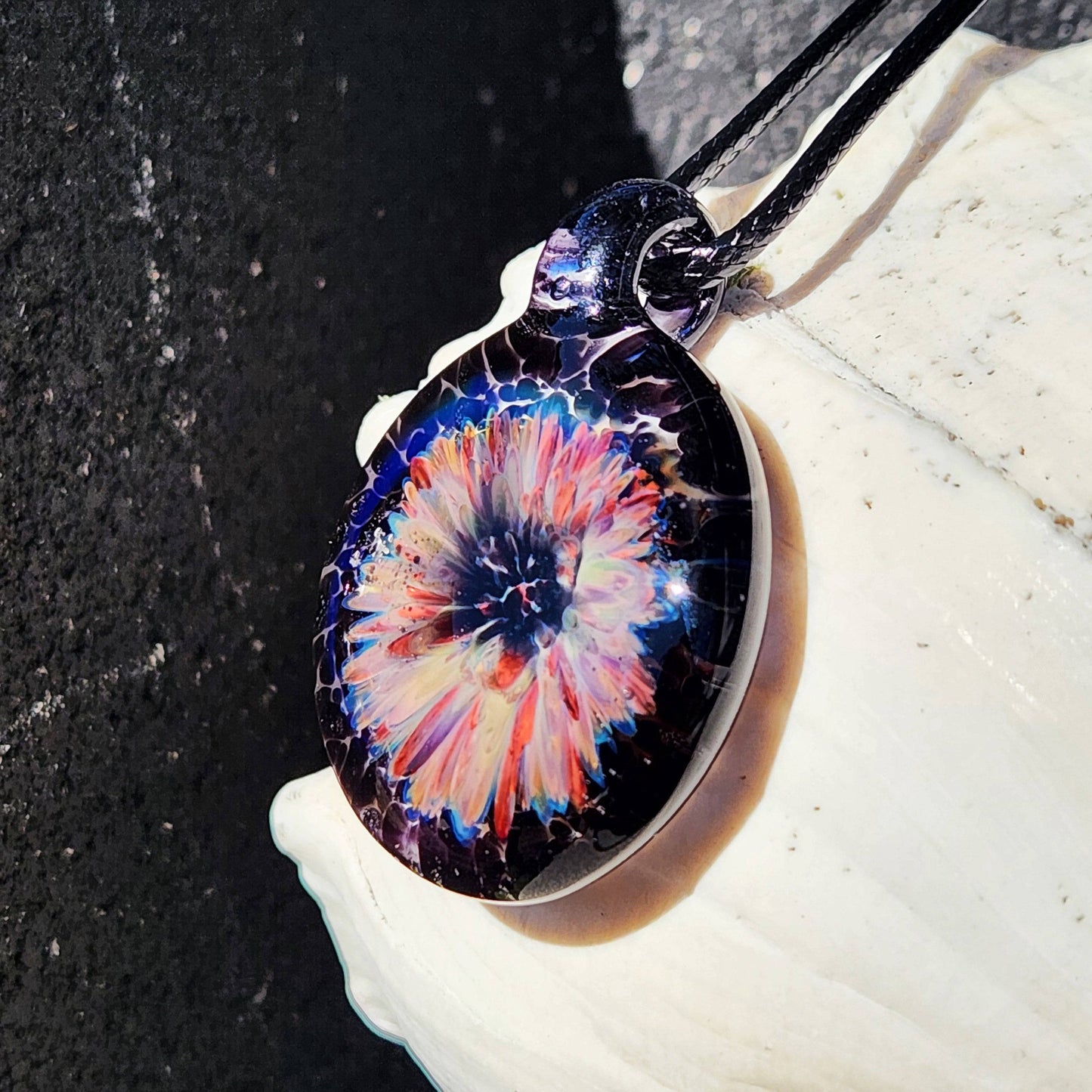 Unique handmade jewelry pendant with a colorful flower encased in black borosilicate glass, ideal for gifting or personal wear.