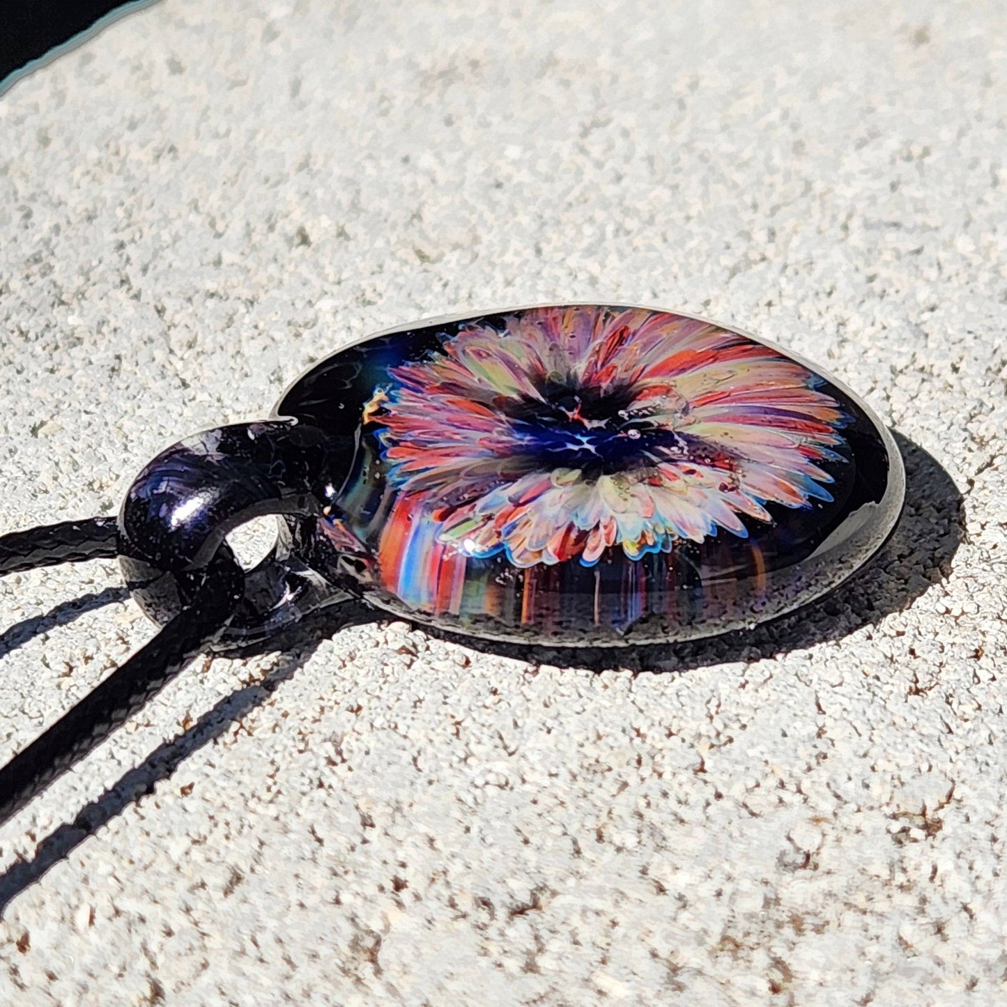 Flat view of handmade blown glass pendant with a multicolor flower design, showcasing the depth and clarity of the borosilicate glass.