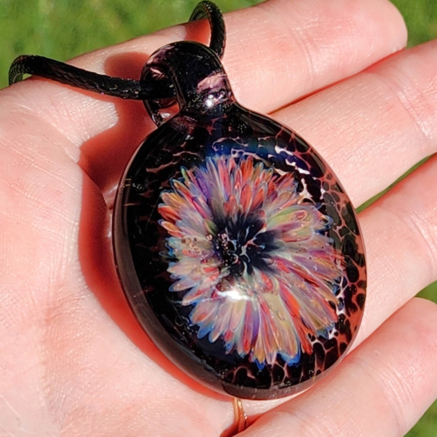 Captivating borosilicate glass pendant featuring a multicolor floral burst on a dark base, ideal handmade gift necklace from DragonFire Glass.