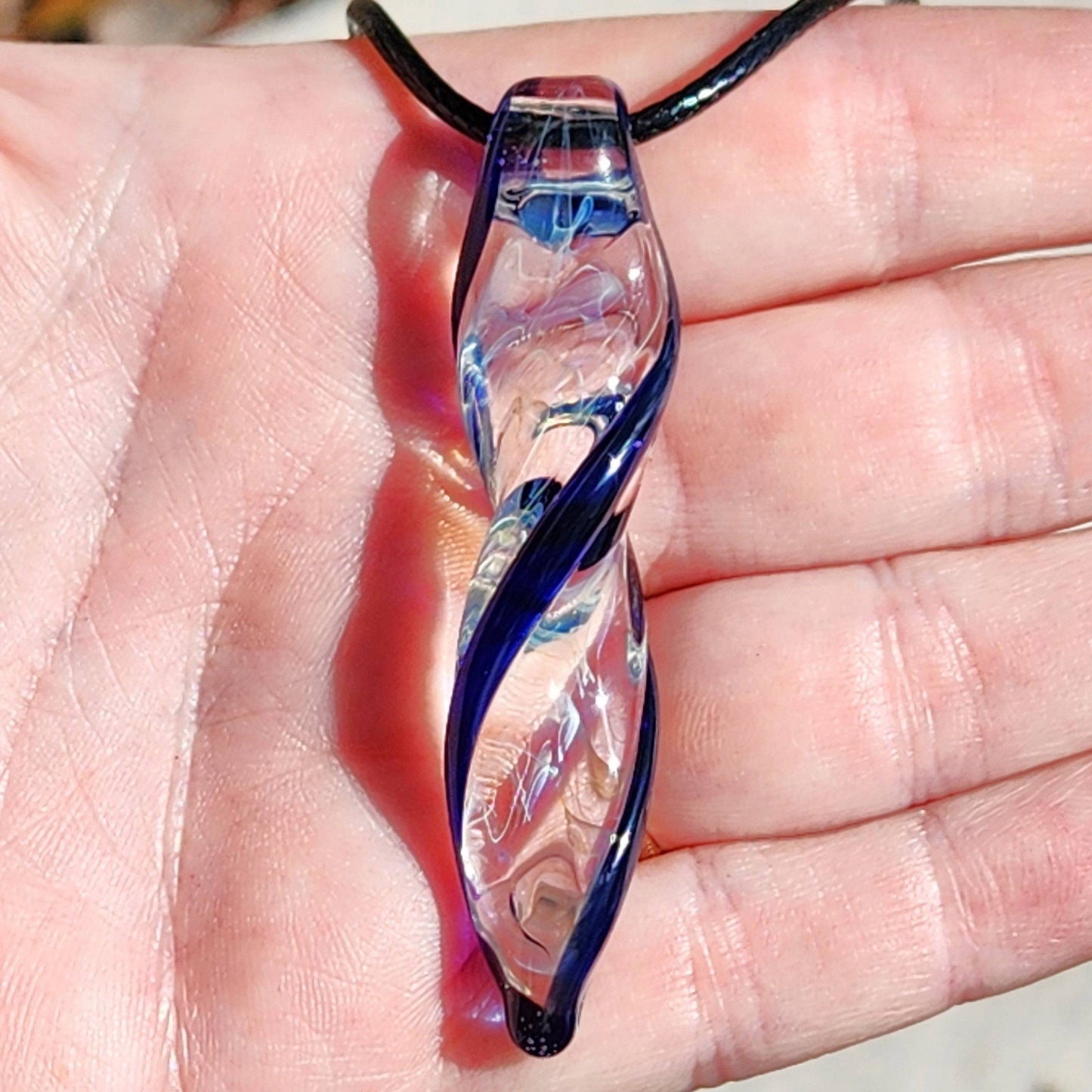Blown Glass Spiral Pendant – Silver Fumed Design with Blue Accents, held in hand to show size and intricate craftsmanship.