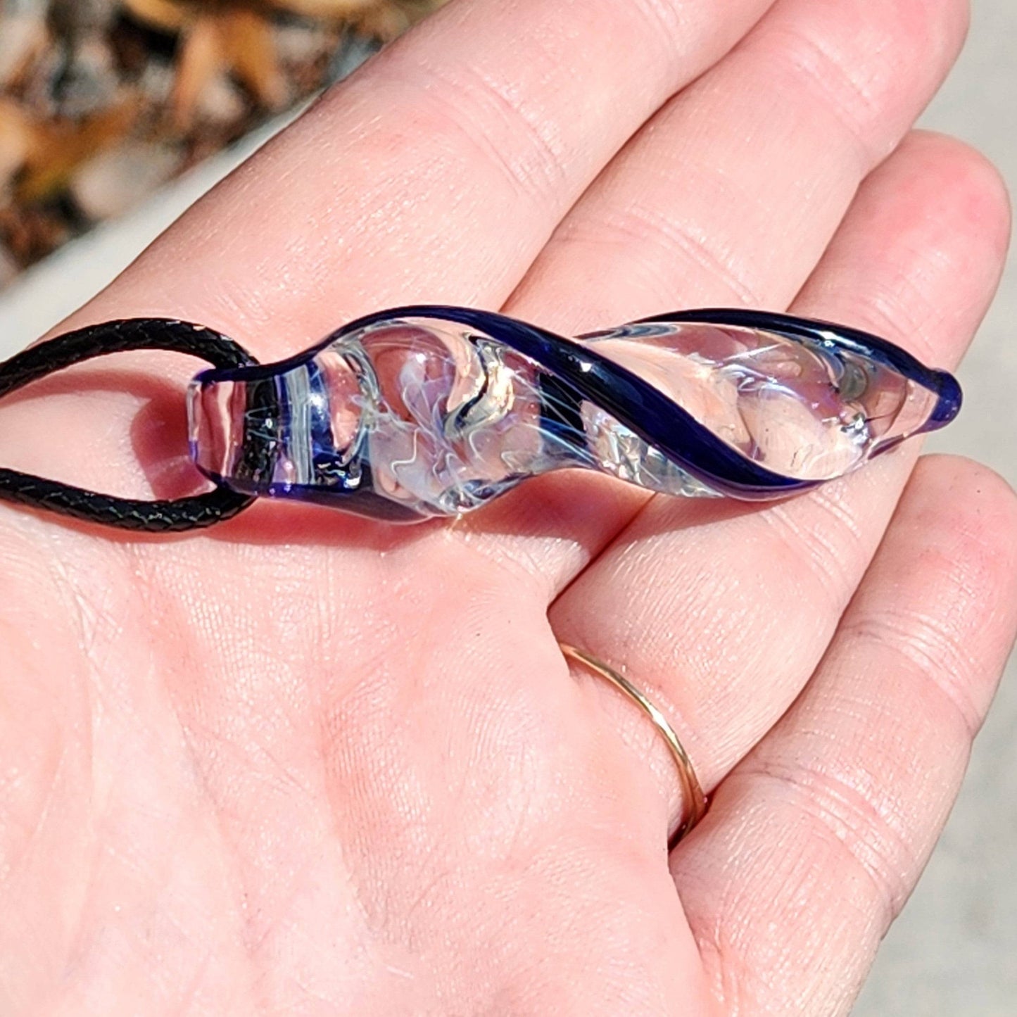Handmade Blown Glass Spiral Pendant with silver-fumed interior and blue spiral, shown in palm for scale and detail.