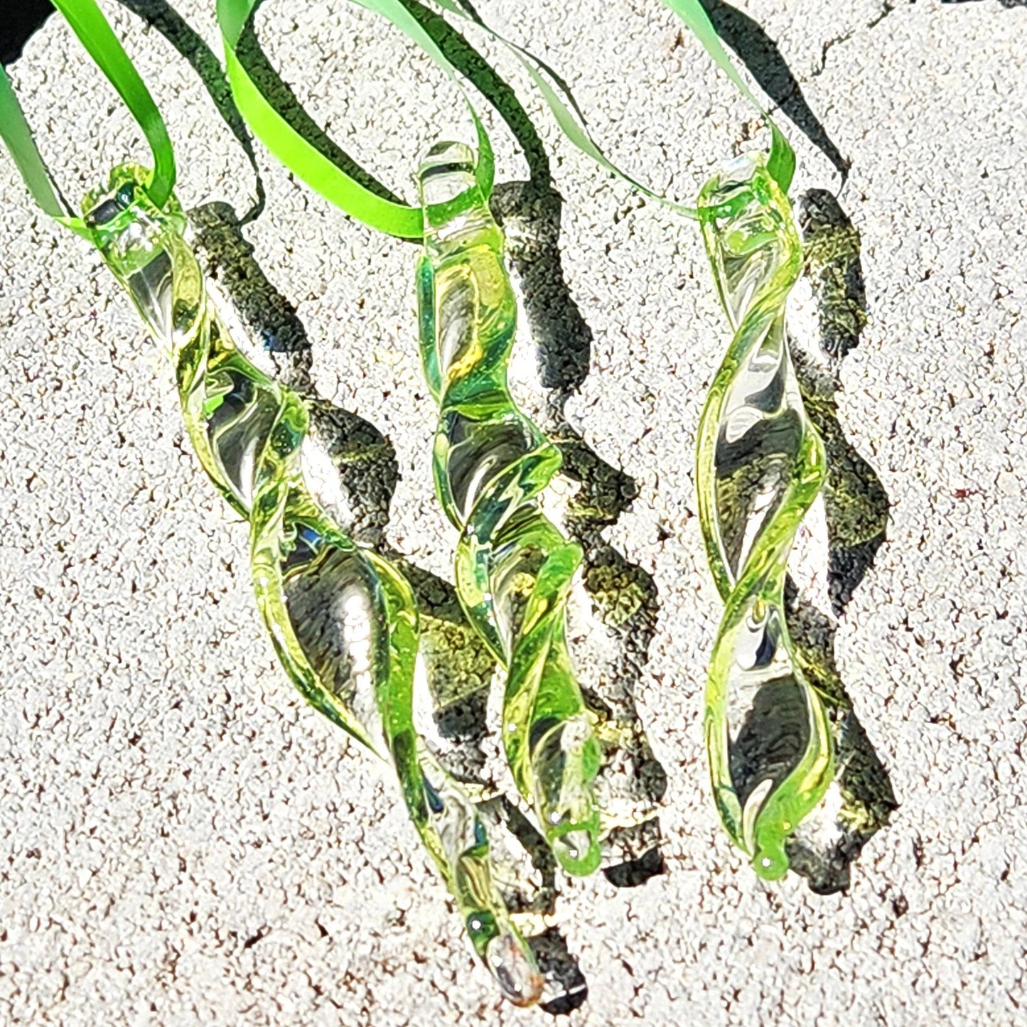 Set of 3 lime green spiral glass suncatchers on a sunlit stone surface, perfect for handmade garden art and gifting.