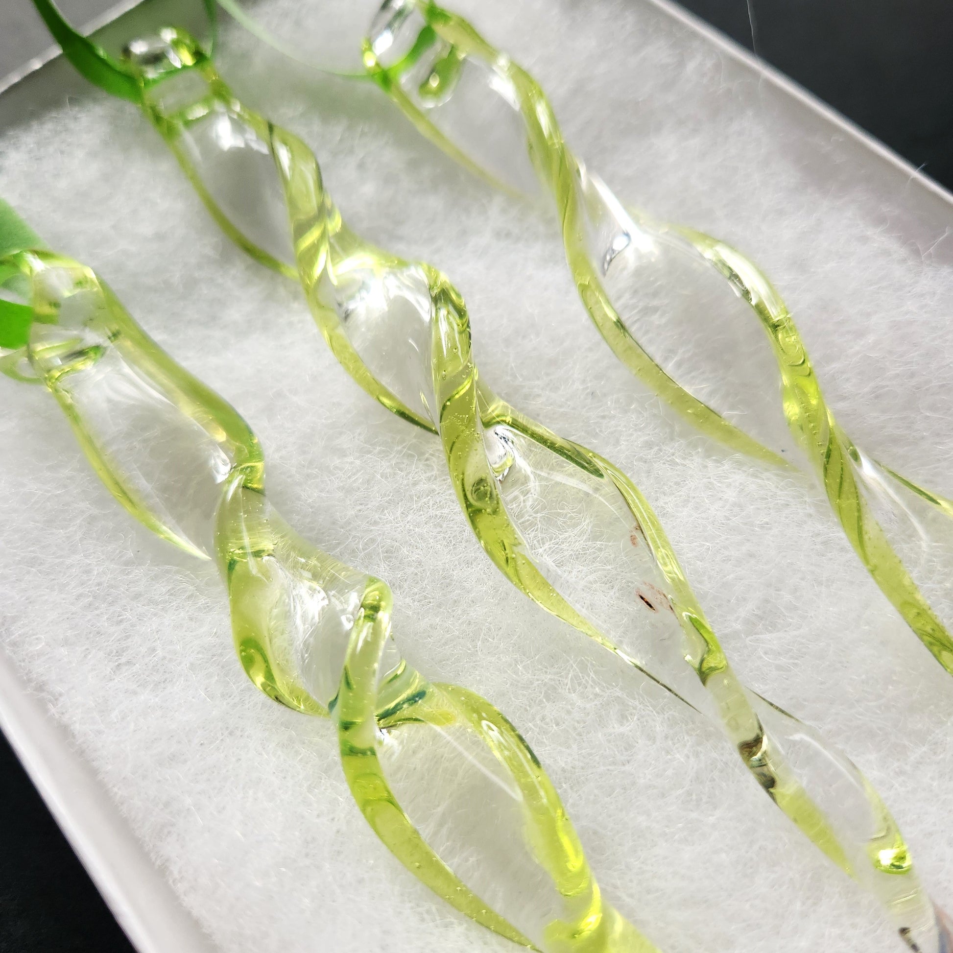 Detailed view of lime green spiral glass suncatchers in a white box, emphasizing their handcrafted quality and elegant curves.