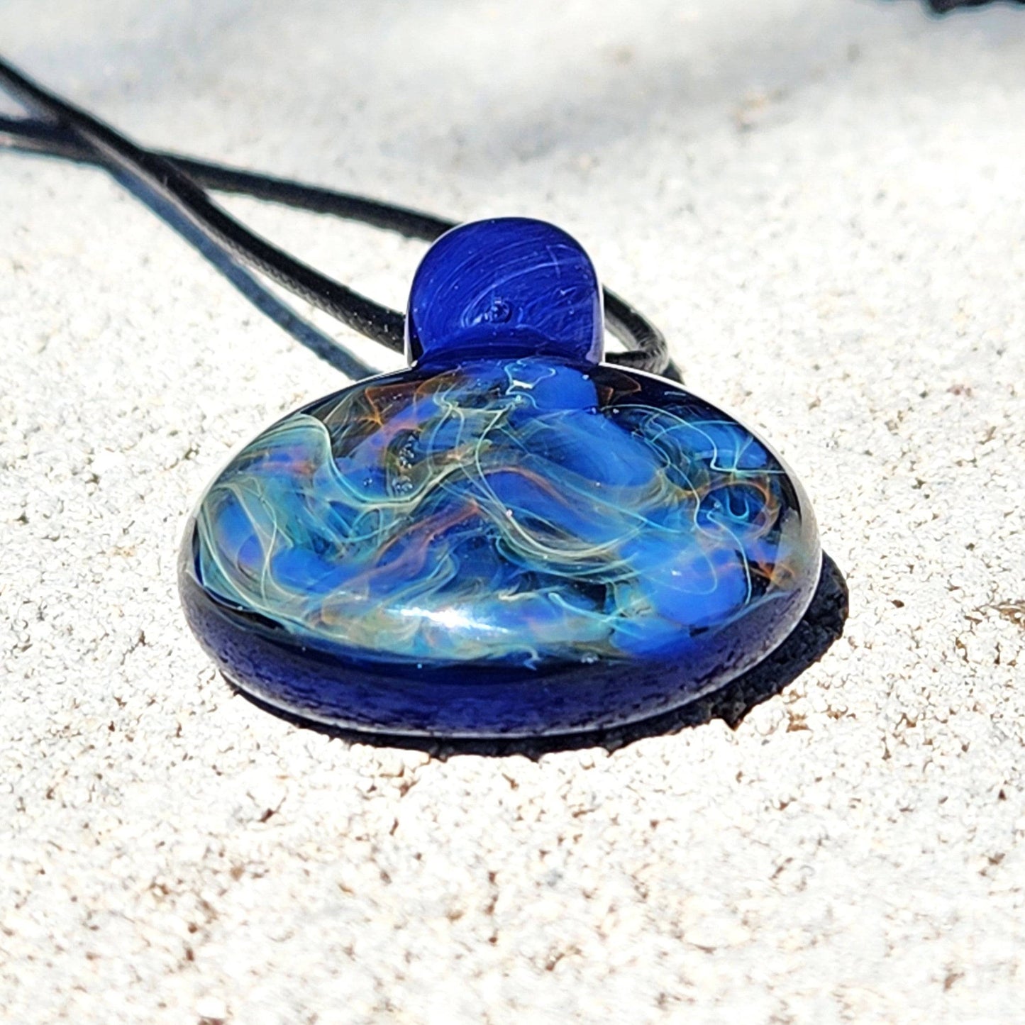 Low-angle view of blown glass pendant with swirling blue and gold fuming, showcasing its glossy, handcrafted finish.