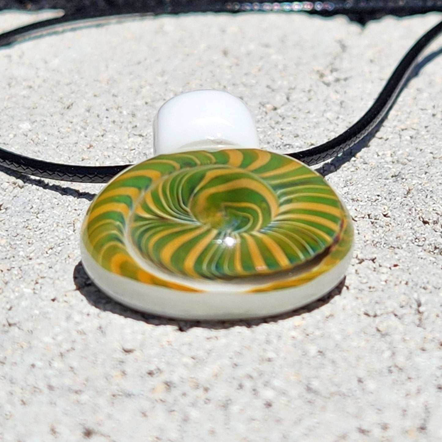Bottom view of Handmade Spiral Glass Pendant with green and yellow spiral, highlighting its smooth, rounded glass finish.