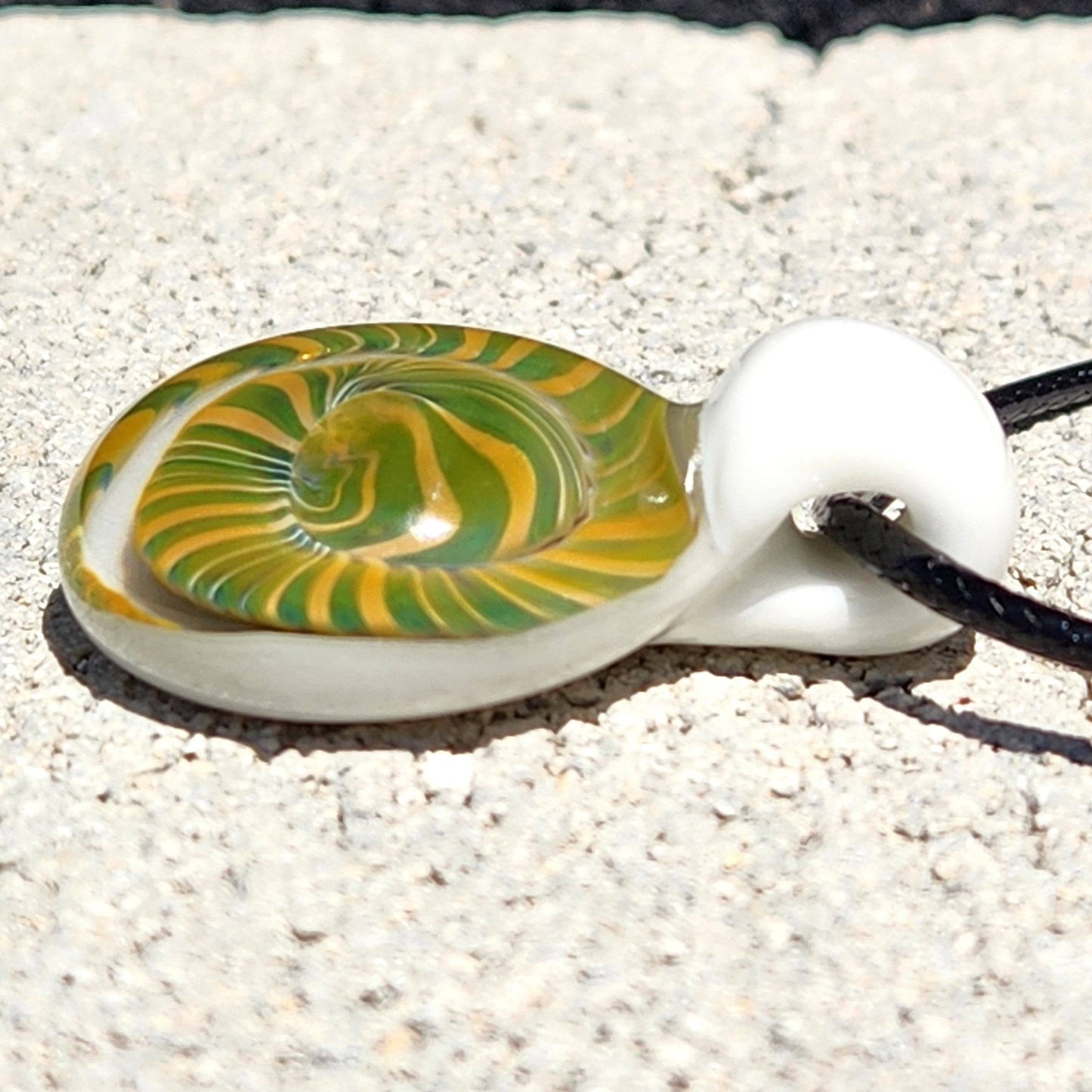 Side view of Handmade Spiral Glass Pendant with green-yellow swirl and white loop, highlighting its smooth glass craftsmanship.