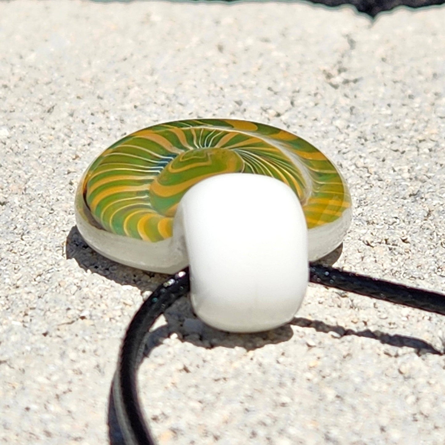 Back view of Handmade Spiral Glass Pendant showing white loop and green-yellow swirl, perfect for unique necklace designs.