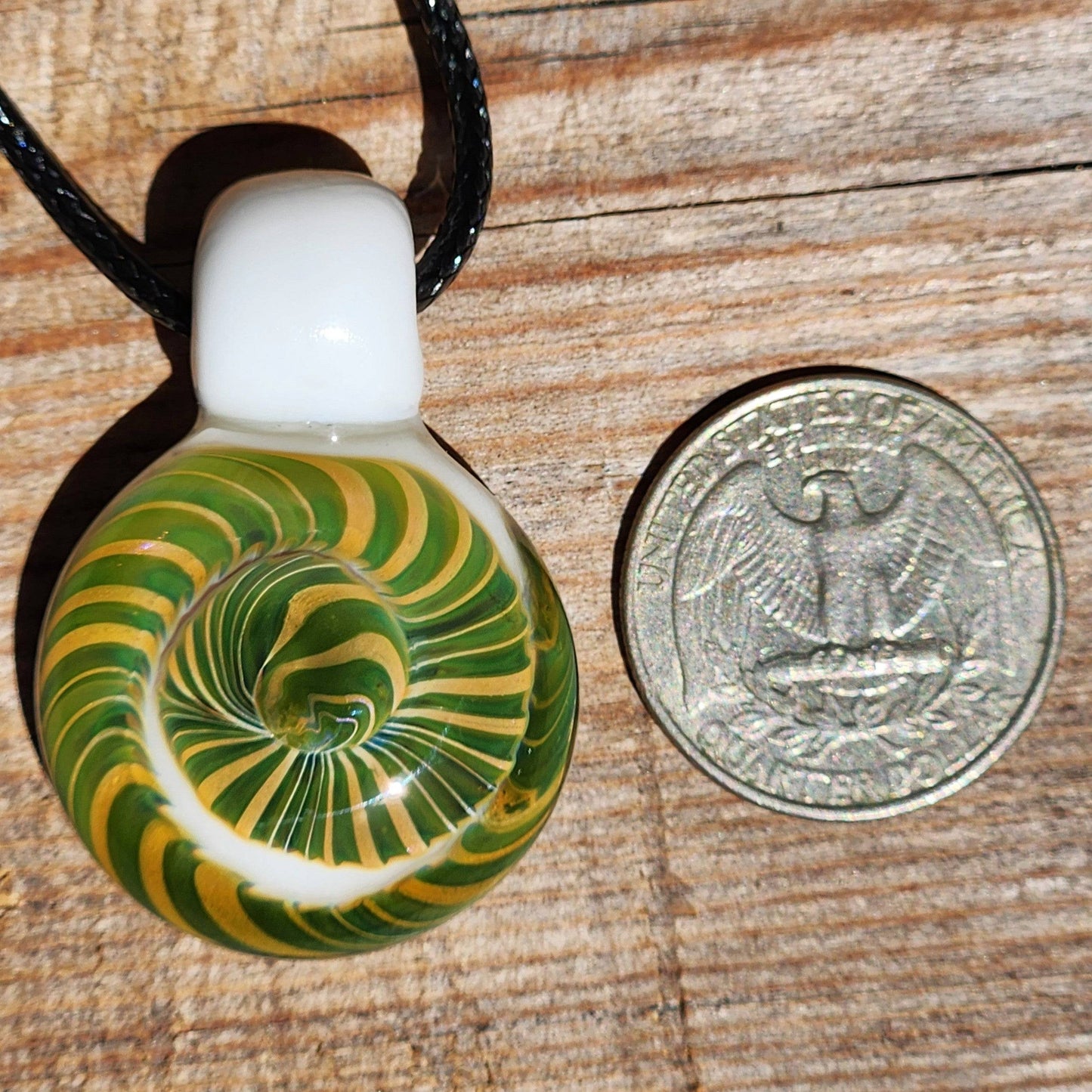 Handmade Spiral Glass Pendant next to a US quarter for size comparison, featuring green-yellow spiral and white glass top.