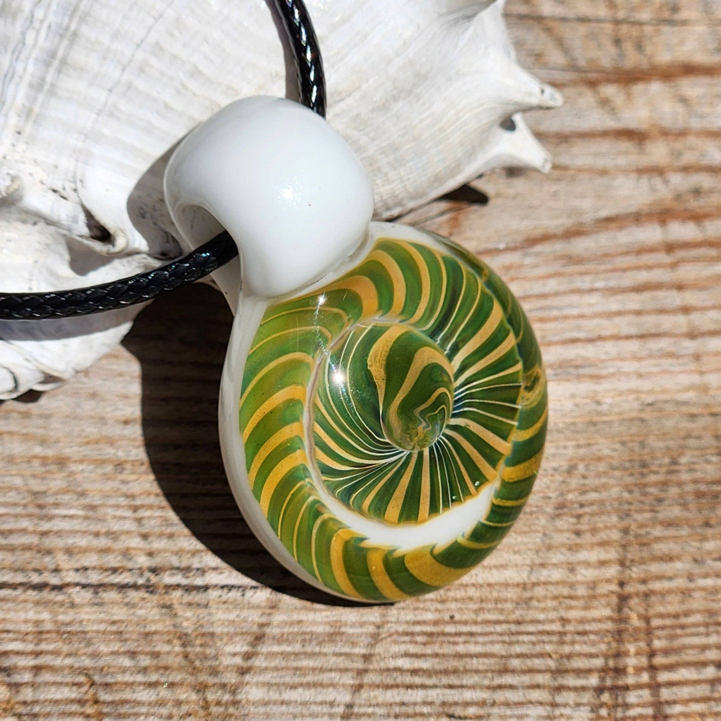 Handmade Spiral Glass Pendant with vivid green-yellow spiral on white base, displayed on wood surface for jewelry showcase.