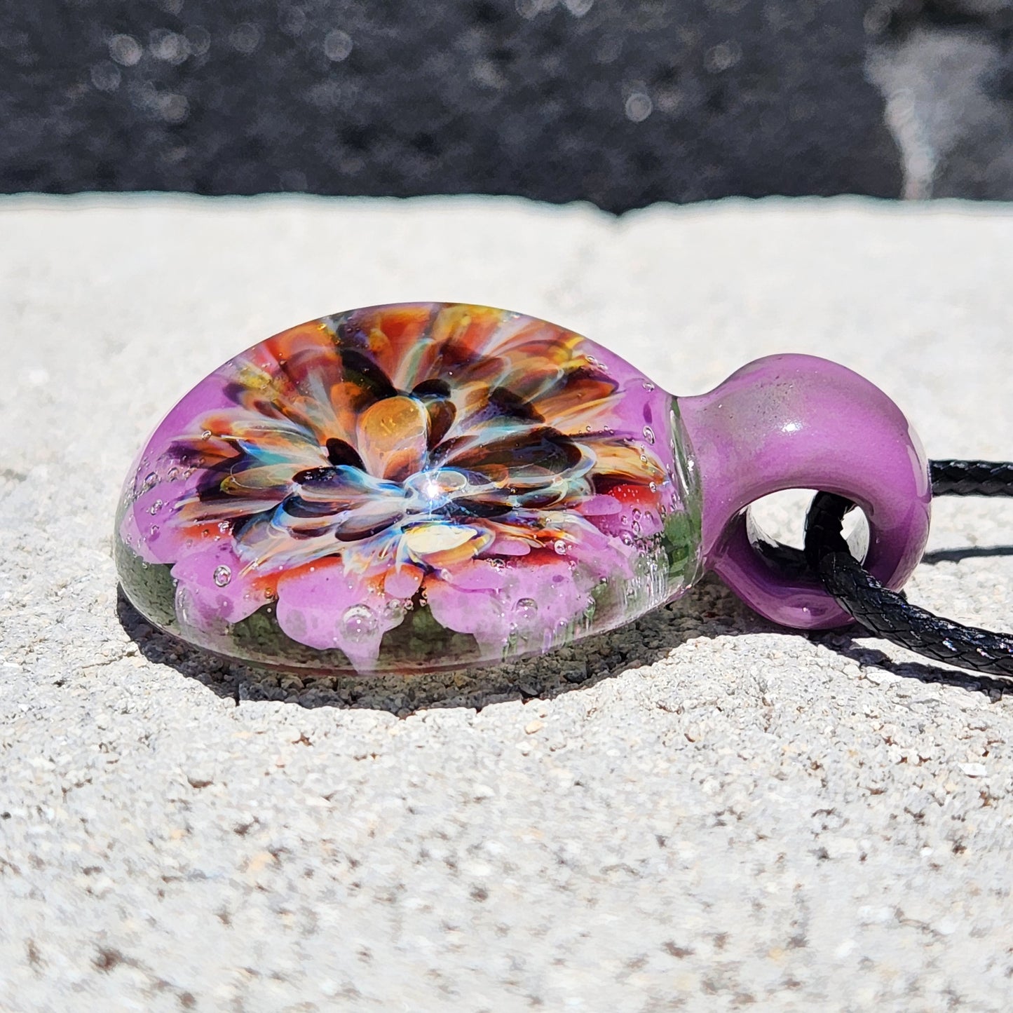 Side profile of handmade multicolor glass pendant with domed flower design. Unique borosilicate necklace for gifting or personal wear.