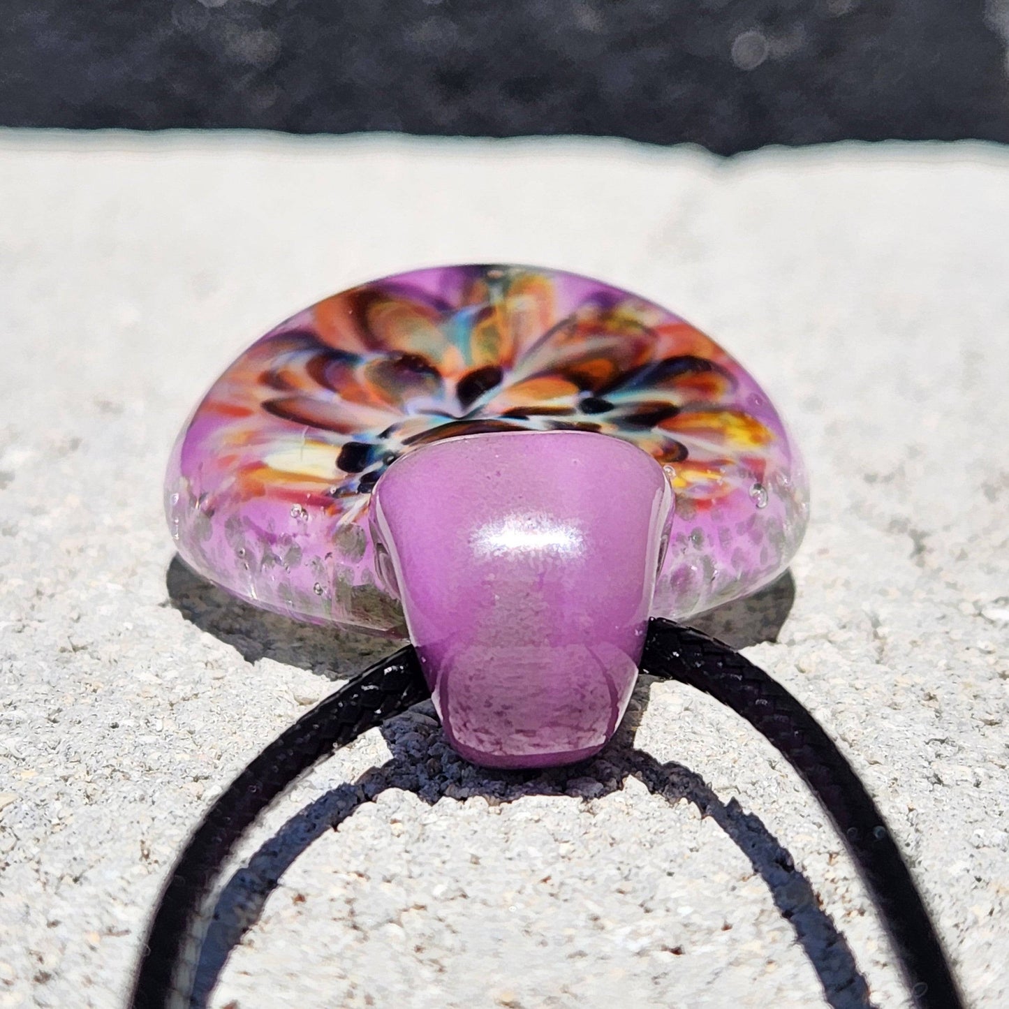 Side view of handmade multicolor glass pendant showing domed flower design and purple loop. Artistic borosilicate jewelry for gifting.