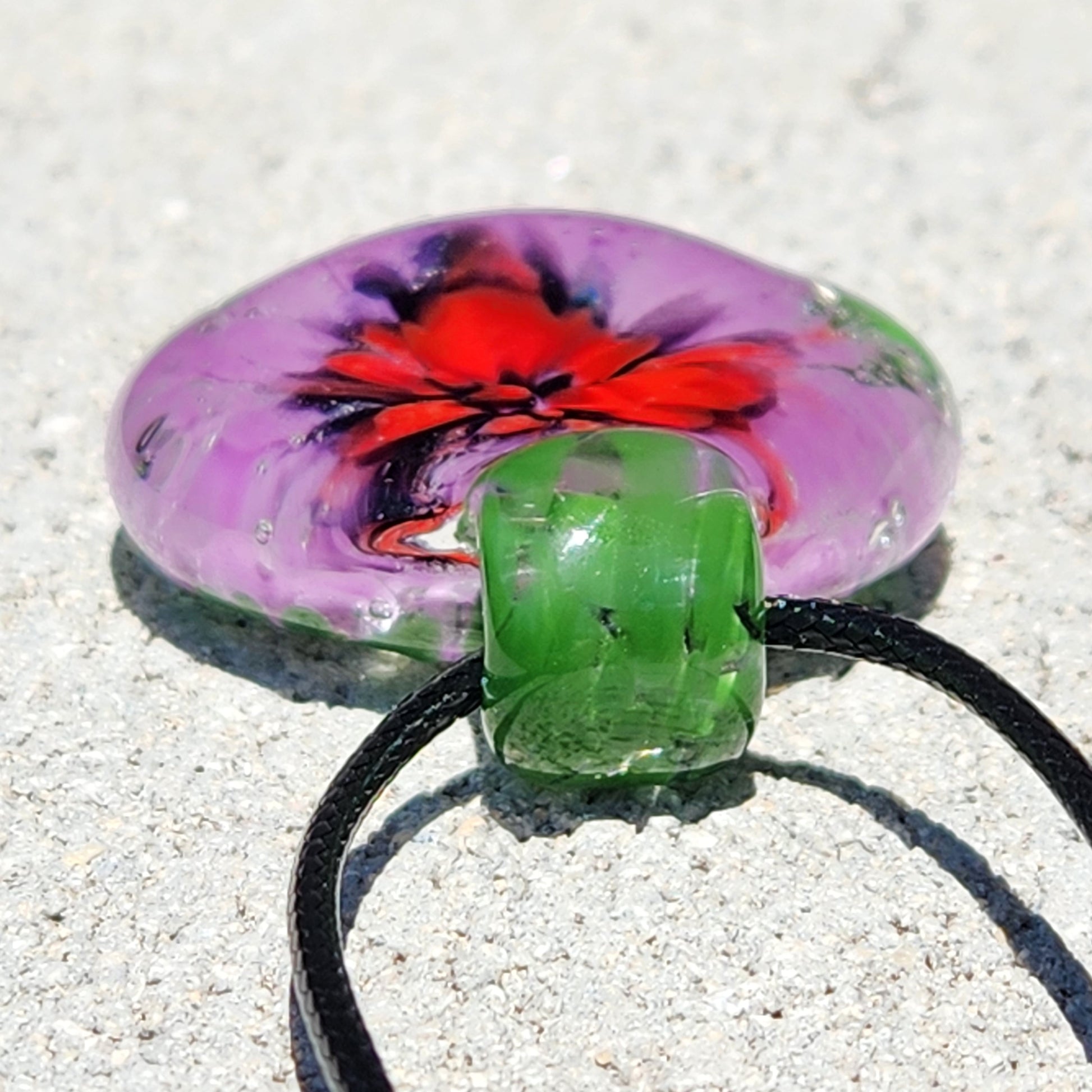 Close-up of green glass loop on Large Heady Glass Pendant Necklace. Features red and purple floral design in handmade borosilicate glass.