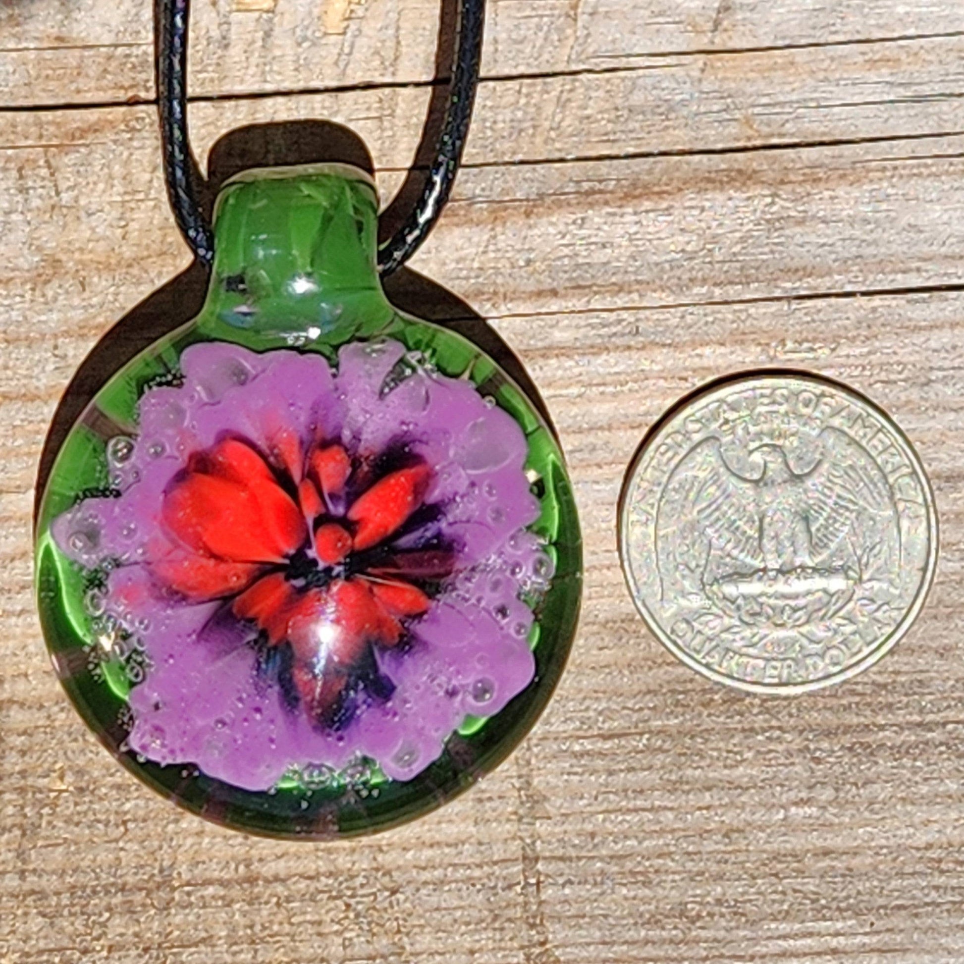 Size comparison of Large Heady Glass Pendant Necklace next to a US quarter. Features red, purple, and green handmade blown glass design.