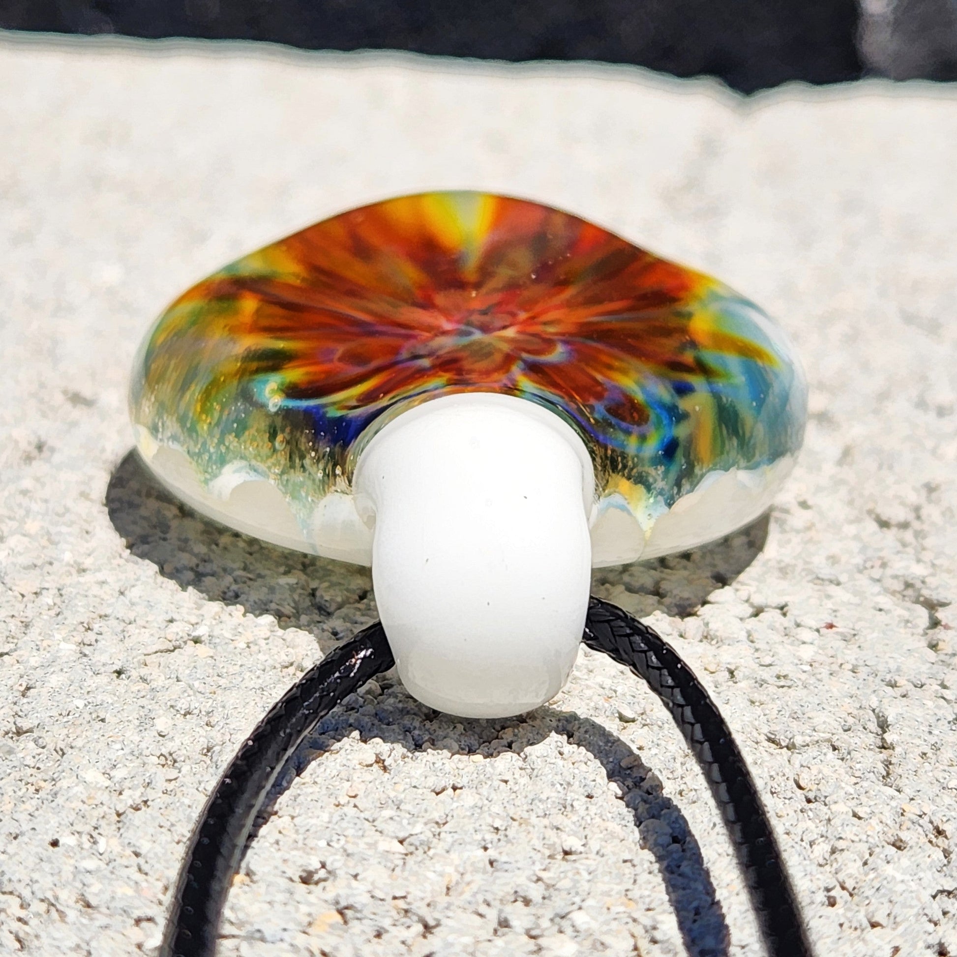 Bottom view of handmade glass pendant showing white loop and colorful swirl pattern. Unique lampworked jewelry beauty in glass.
