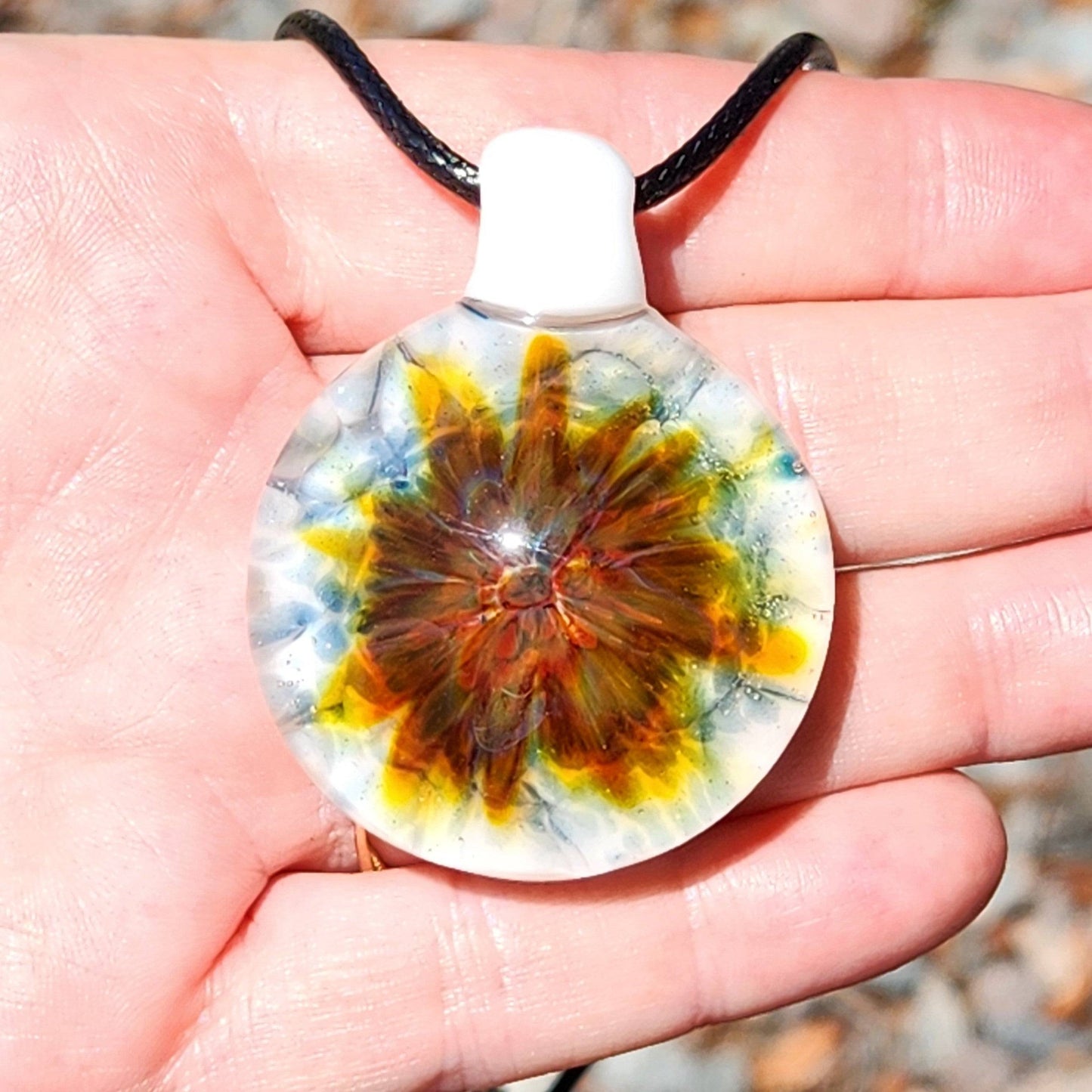 Front view of handmade blown glass pendant with fiery floral swirl and white base. Unique lampworked jewelry beauty in glass.