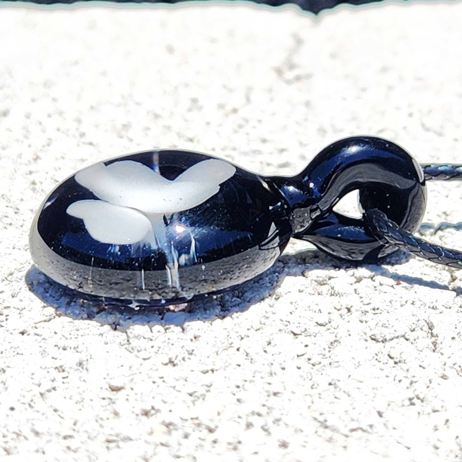 Low-angle view of Small Black and White Glass Pendant highlighting its curved shape and butterfly motif, ideal for gifting.