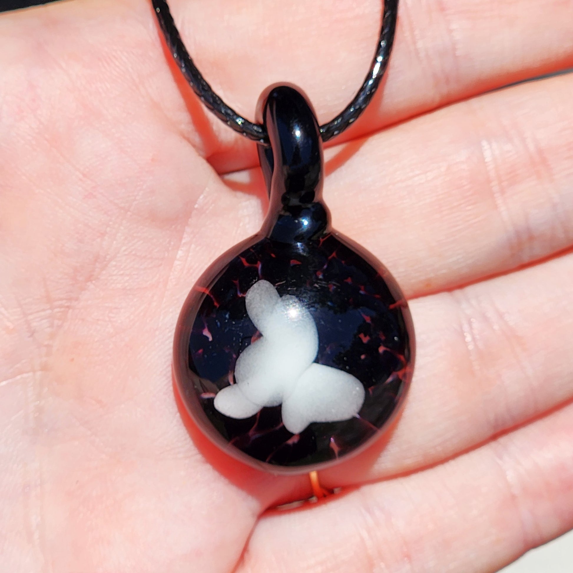 Small Black and White Glass Pendant shown in hand, featuring a white butterfly on glossy black glass, perfect for statement jewelry.