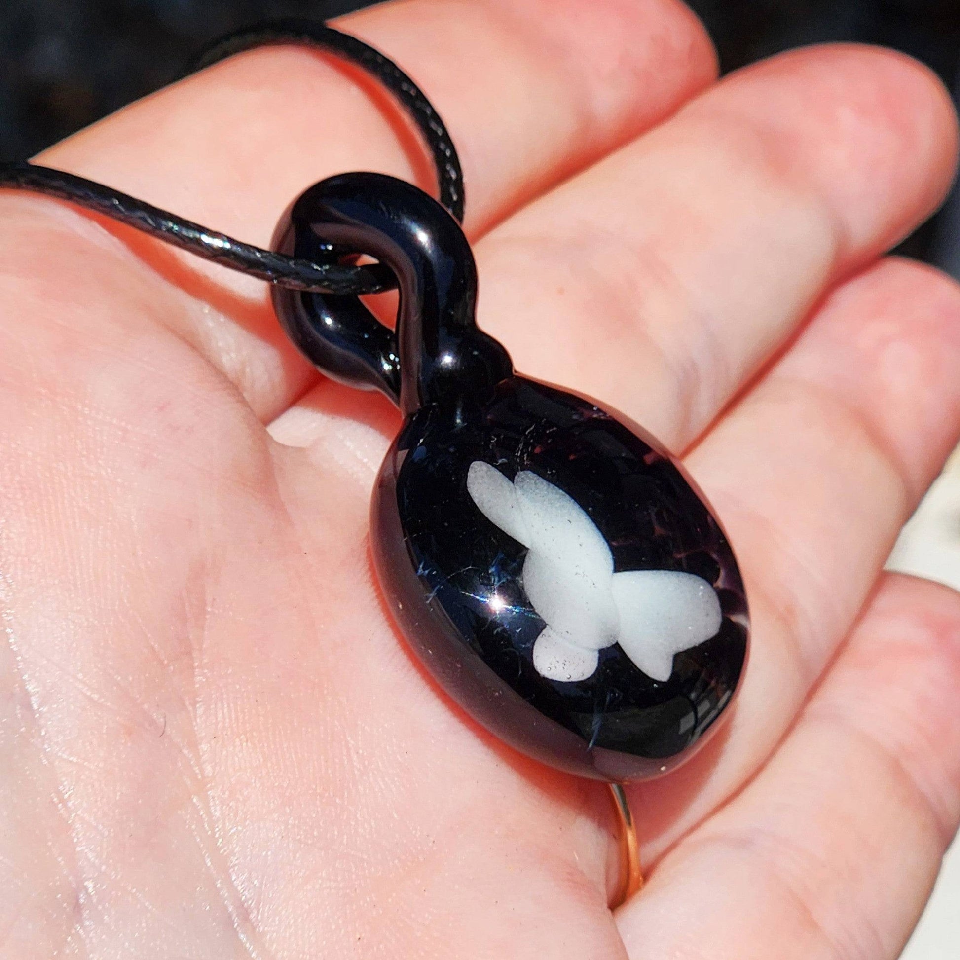 Handheld view of Small Black and White Glass Pendant with butterfly design, emphasizing its size and handmade quality.