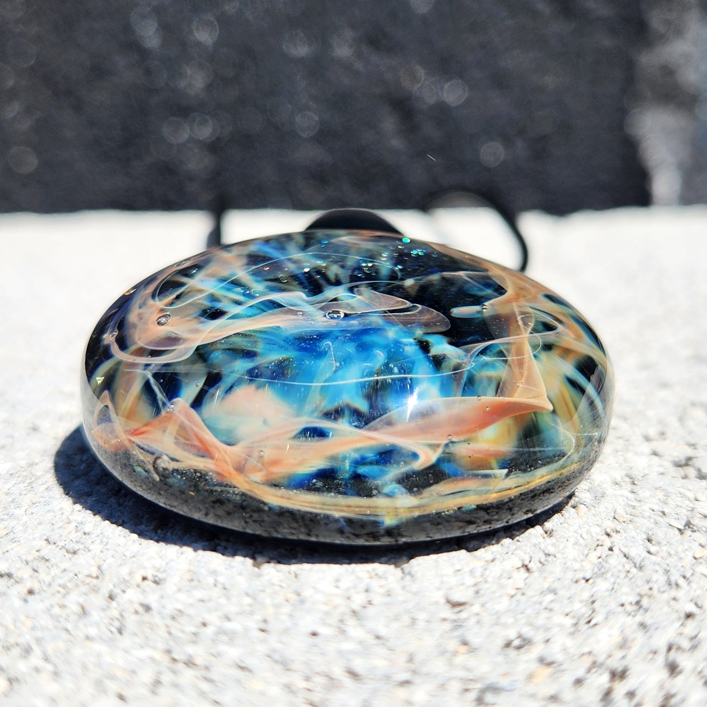 Colorful glass object on a textured surface with a blurred background