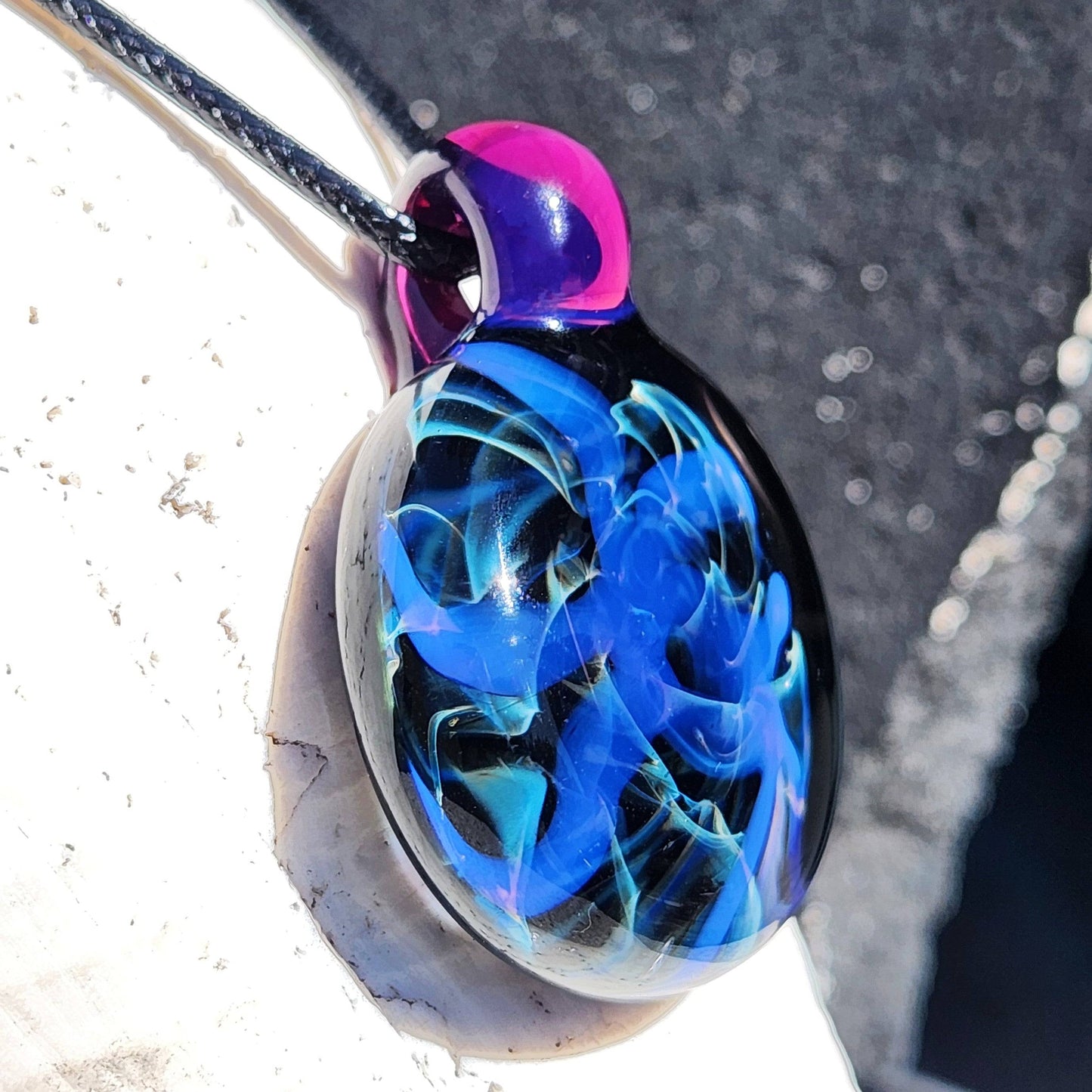 Side view of Handmade Blue Swirl Glass Pendant Necklace showing intricate color-shifting swirls and glossy finish.
