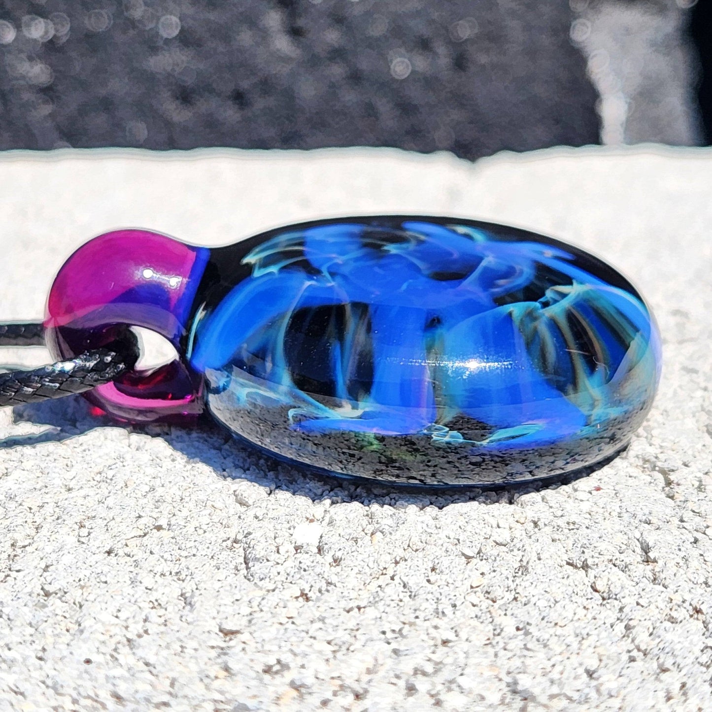 Flat side view of Handmade Blue Swirl Glass Pendant Necklace showing smooth curvature and vibrant blue design.