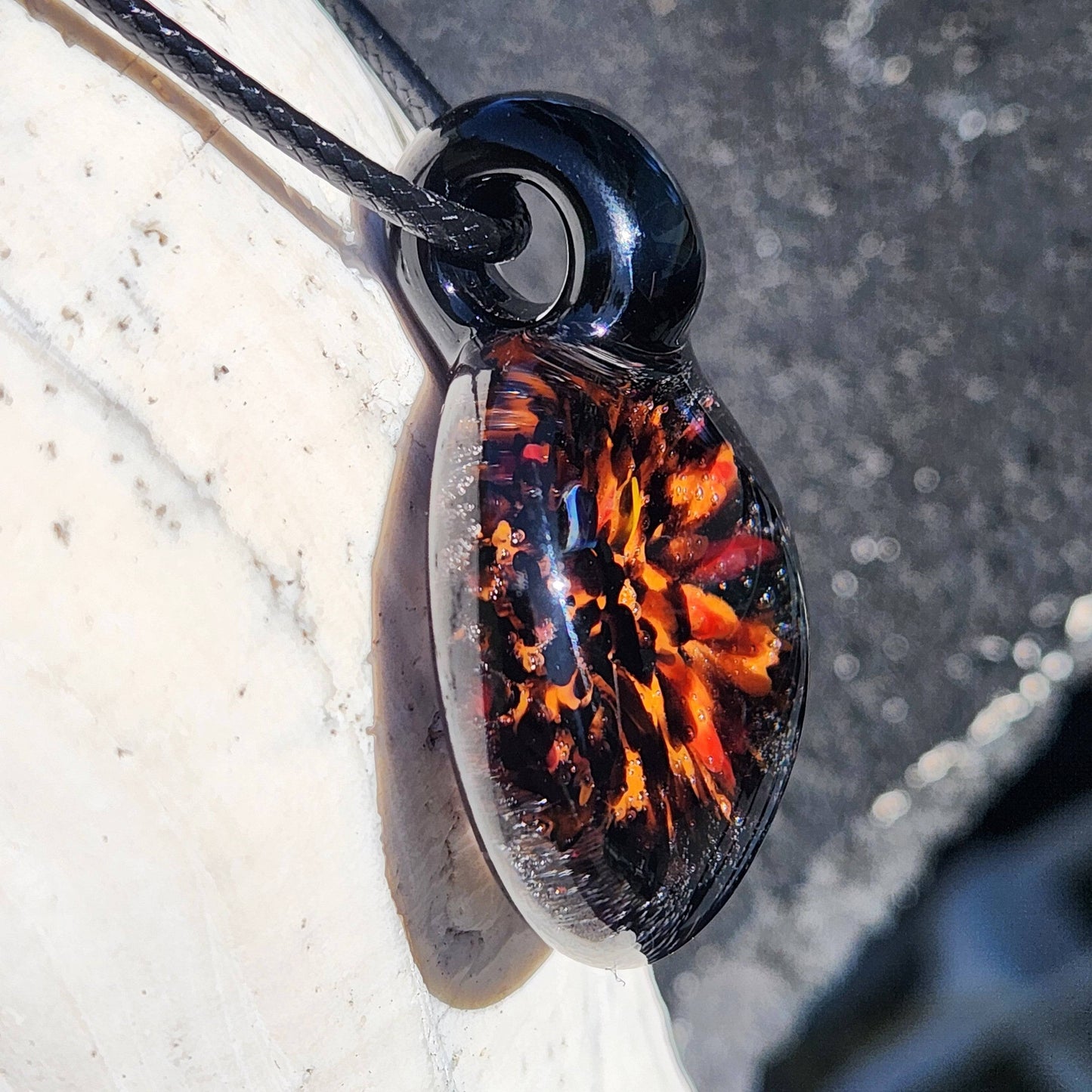 Side view of Fiery Glass Pendant Necklace showing layered orange and red fire bloom in clear domed glass, handcrafted Halloween jewelry.