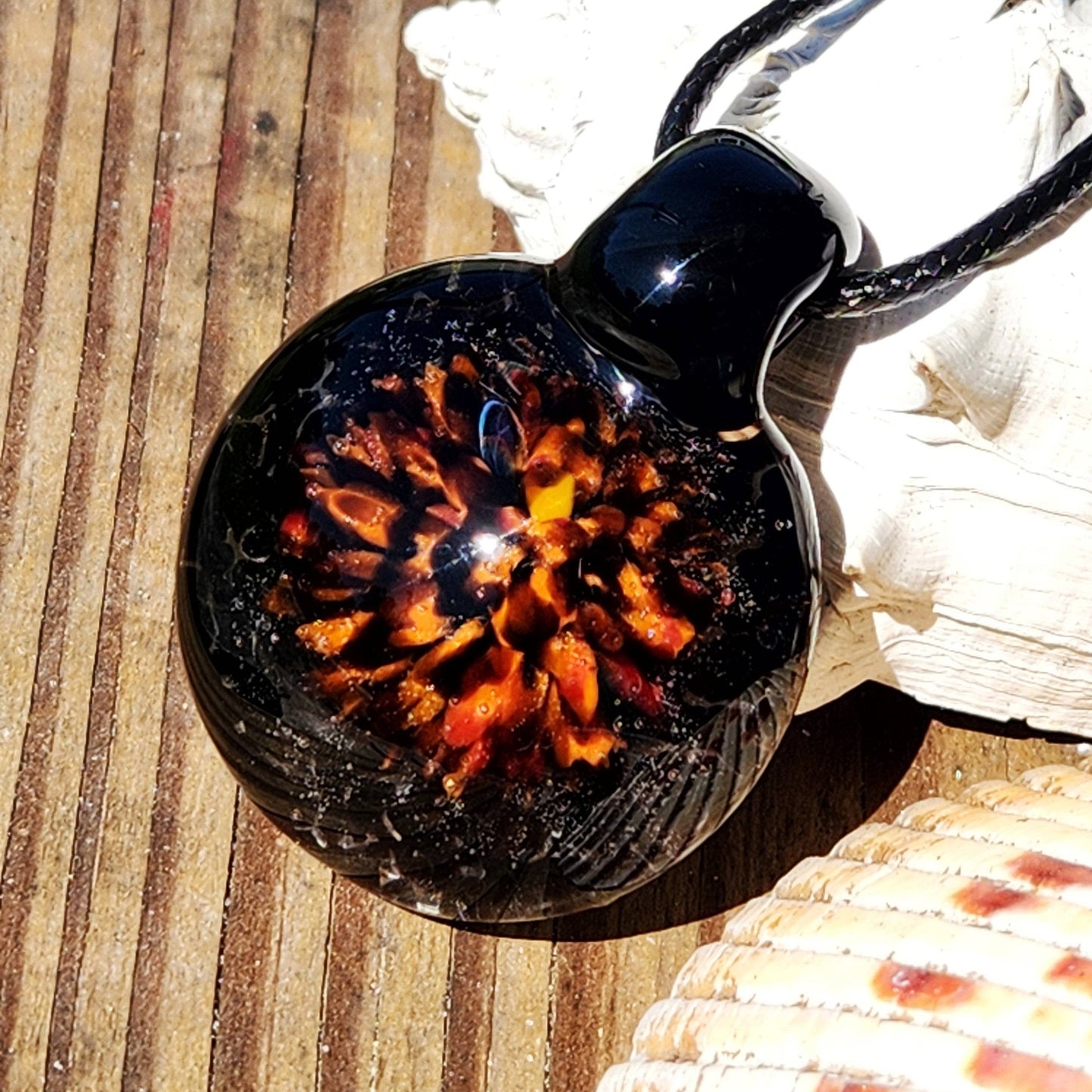 Fiery Glass Pendant Necklace with vivid orange and red fire bloom design on black glass, handmade Halloween-inspired jewelry for fall fashion.