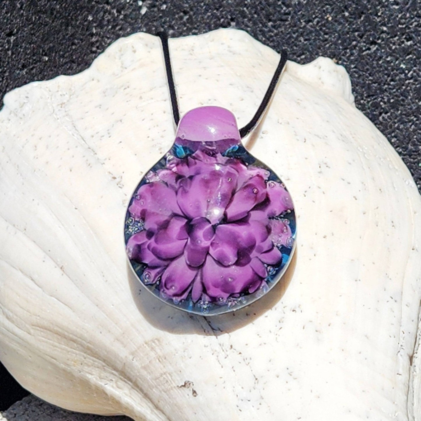 Handblown borosilicate glass pendant necklace featuring a vivid purple and black floral design on a blue background. Unique jewelry gift for women.