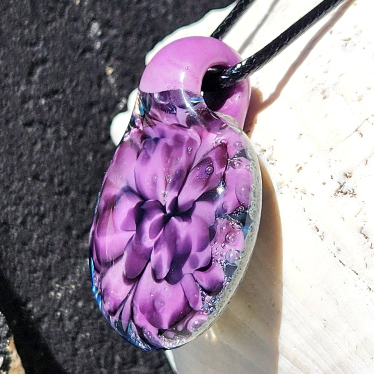 Detailed side angle of floral glass pendant necklace with purple hues and bubble accents. Unique borosilicate charm for gifting.