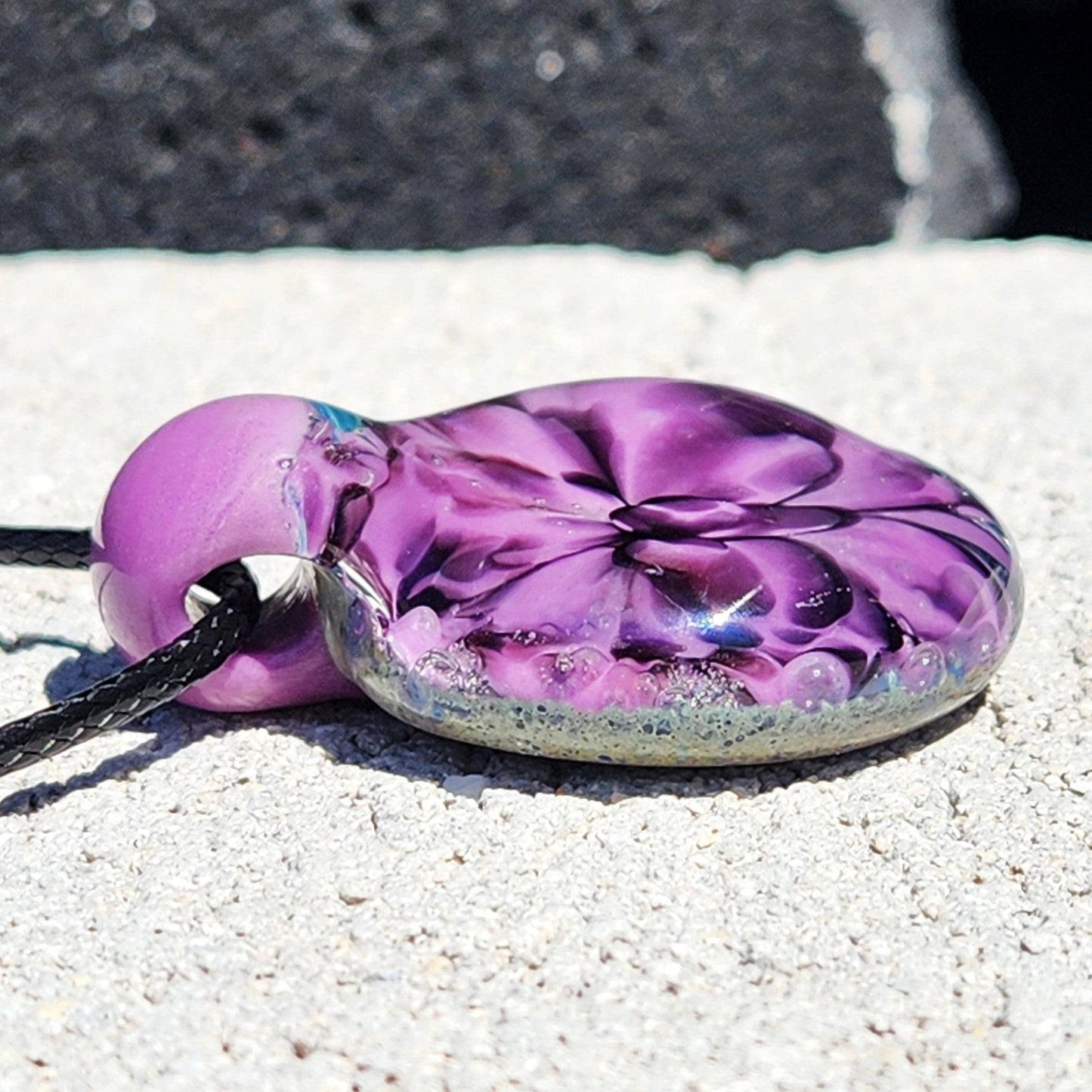 Side view of handblown borosilicate glass pendant showing layered purple petals and smooth glass finish. Unique accessory for jewelry lovers.