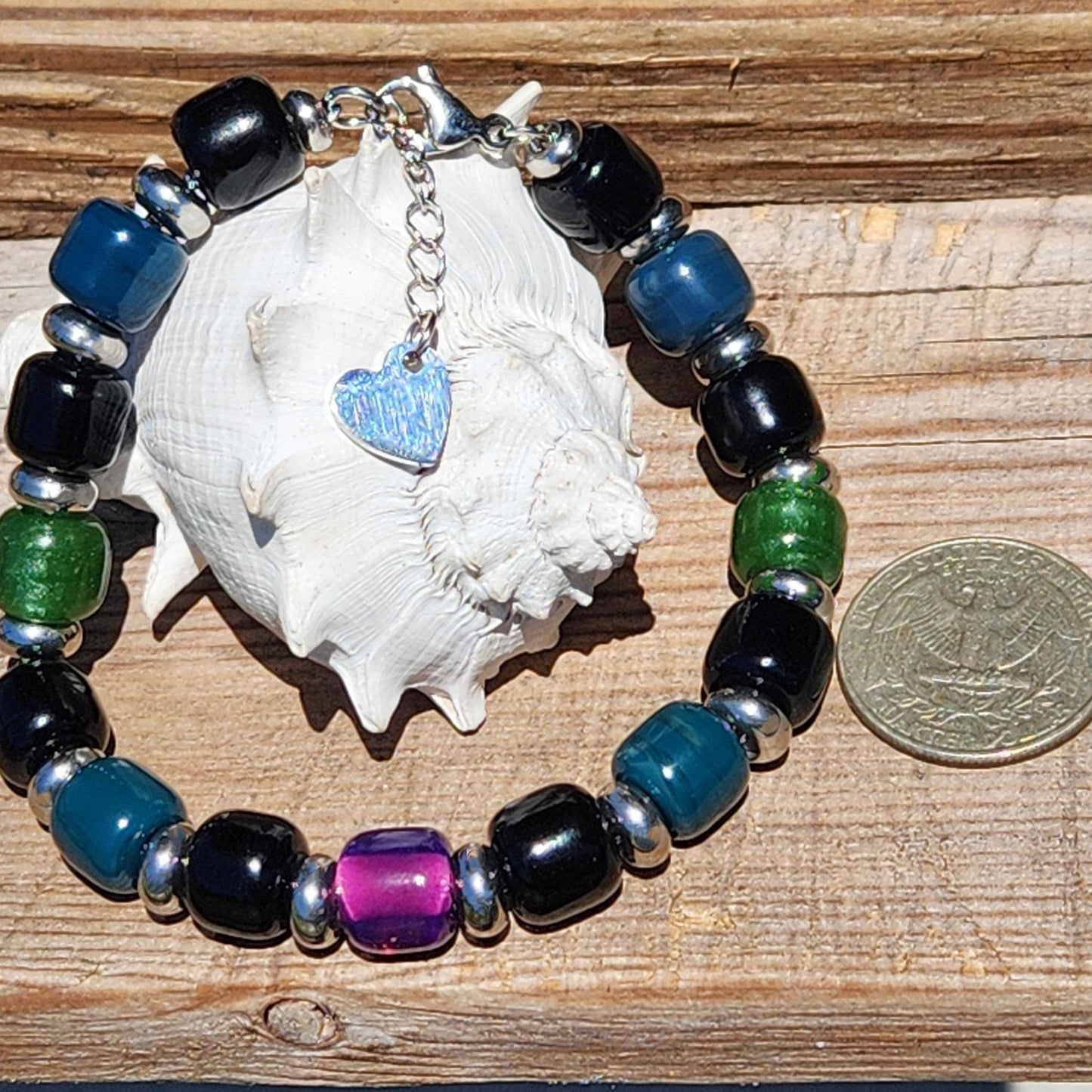 Colorful Boho Glass Beaded Bracelet with heart charm and extender, displayed beside a seashell and coin for size reference.
