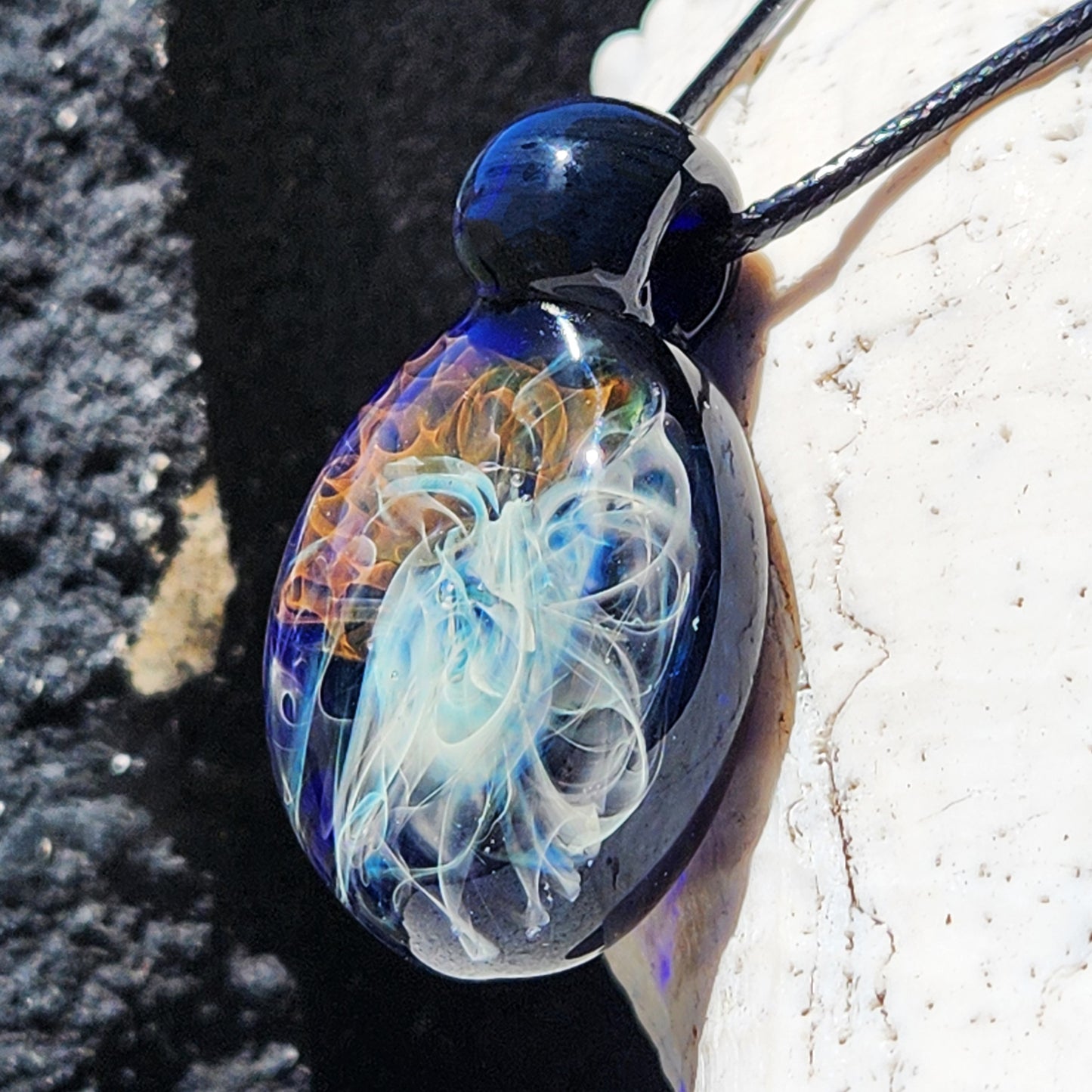Angled view of Gold & Silver Fumed Glass Pendant Necklace with luminous swirling design. Handblown glass pendant in vibrant galaxy colors.