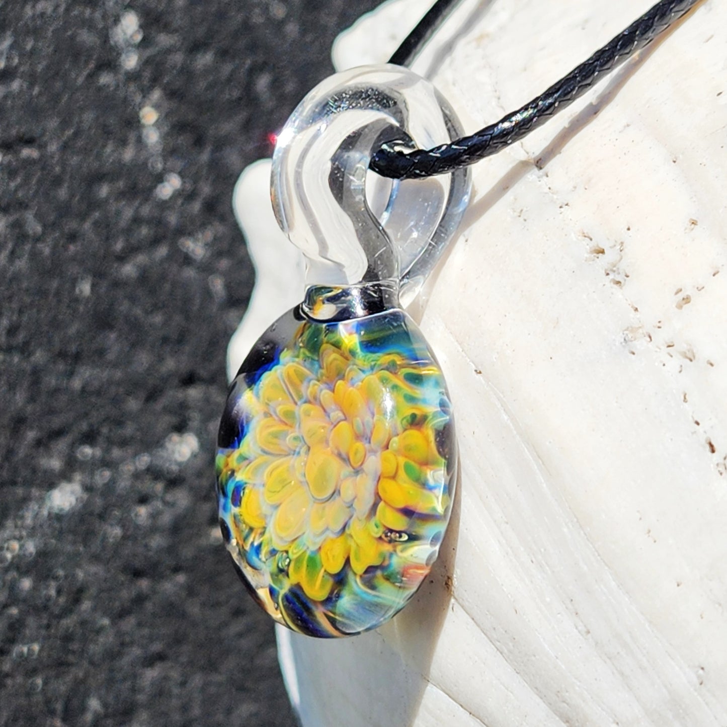 Artisan green glass pendant necklace with vivid multicolor flower design, crafted from blown glass and attached to adjustable cord.
