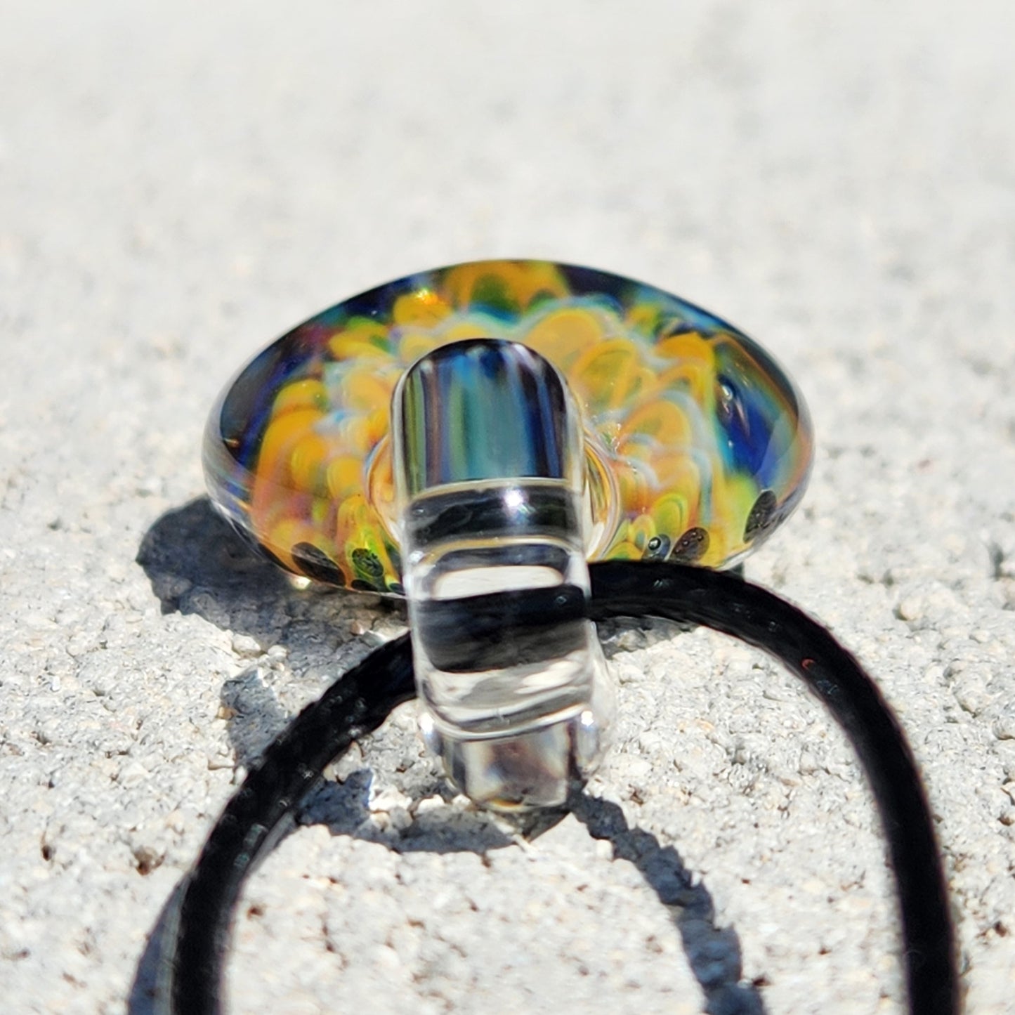 Bottom view of green glass pendant necklace showing transparent loop and colorful flower encased in clear glass.