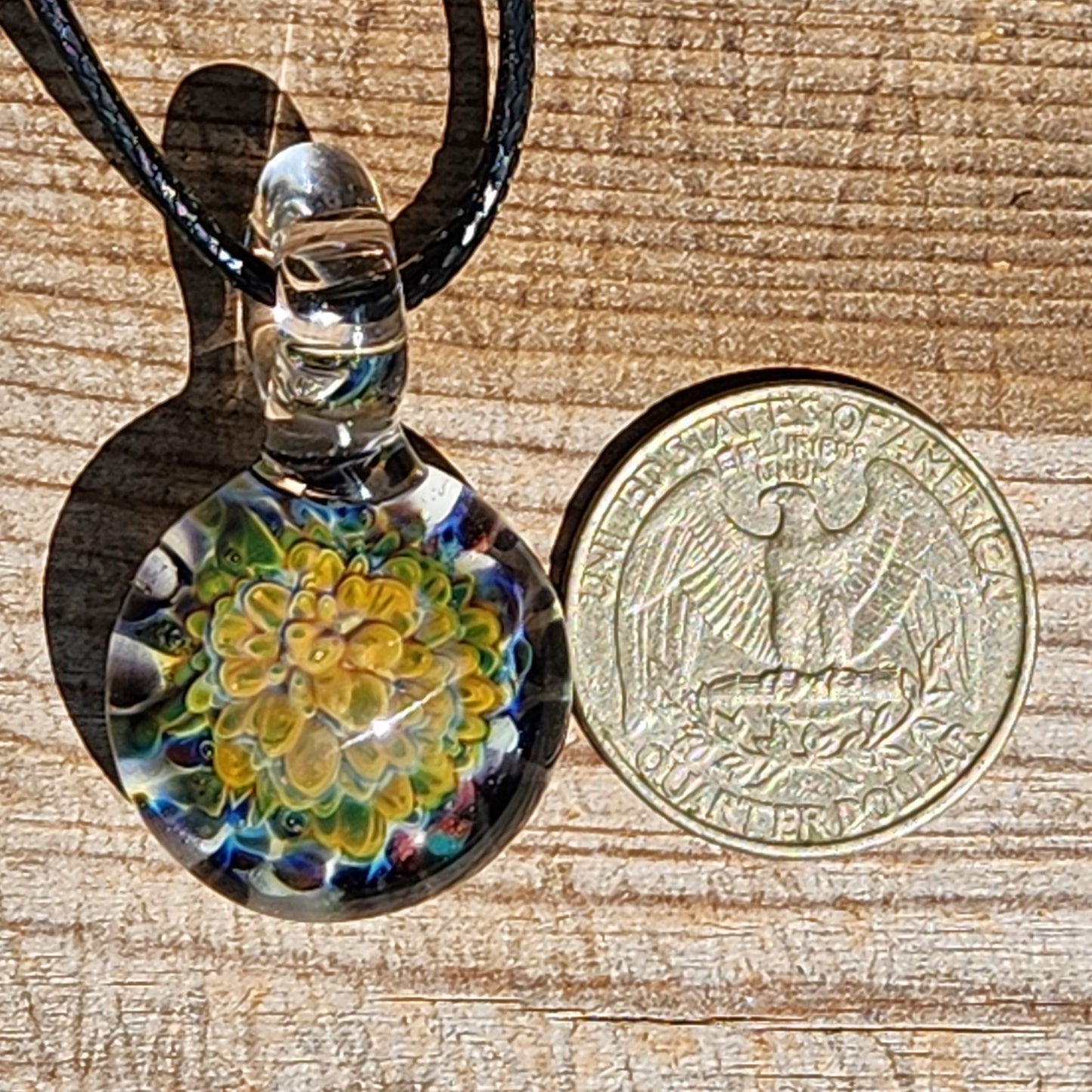 Size comparison of handmade green glass pendant necklace next to a US quarter, showcasing its compact and wearable size.