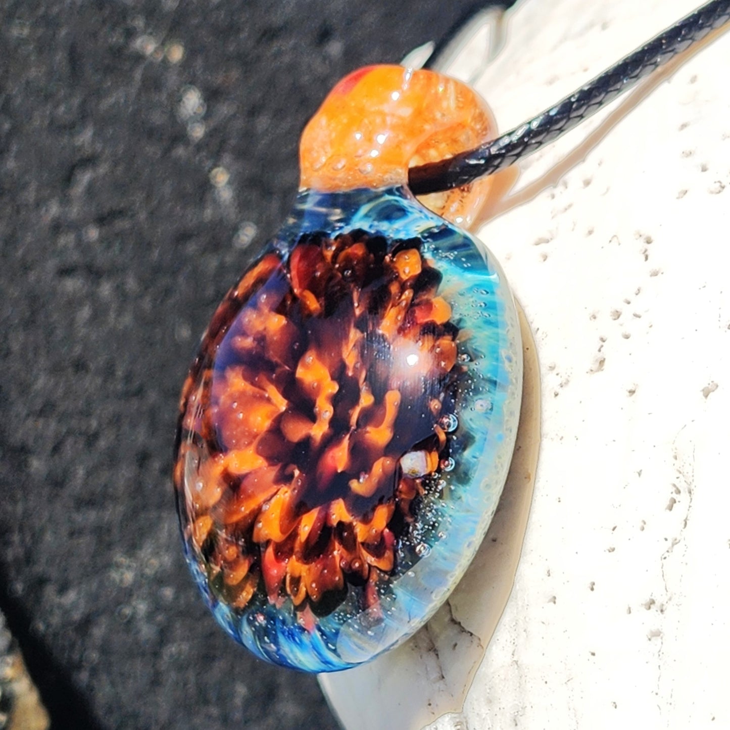 Angled view of multicolor handmade glass pendant with orange and blue tones, ideal for jewelry collections and gift-giving occasions.