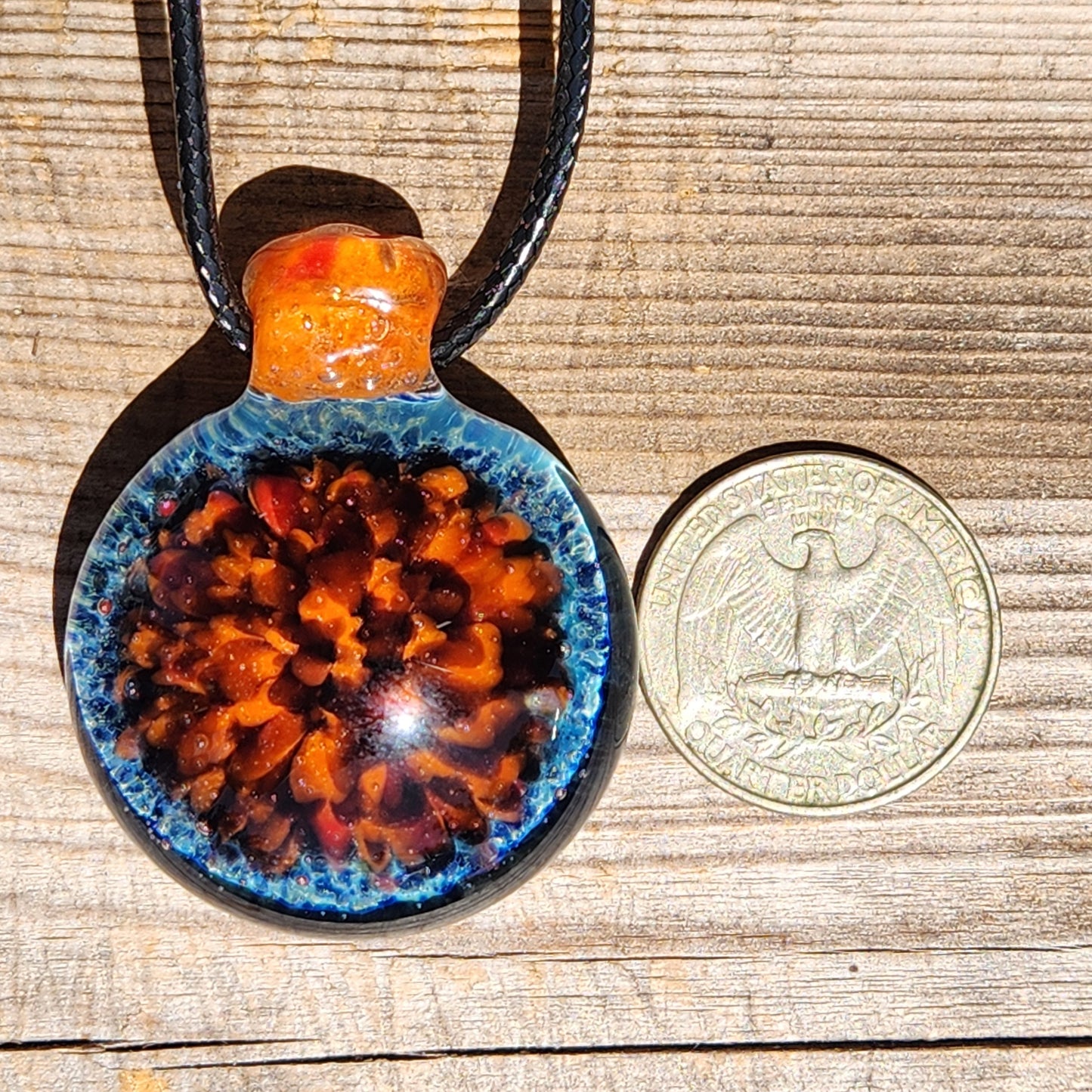 Size comparison of handmade glass pendant next to a US quarter, showcasing detailed crushed borosilicate design. Unique jewelry necklace.