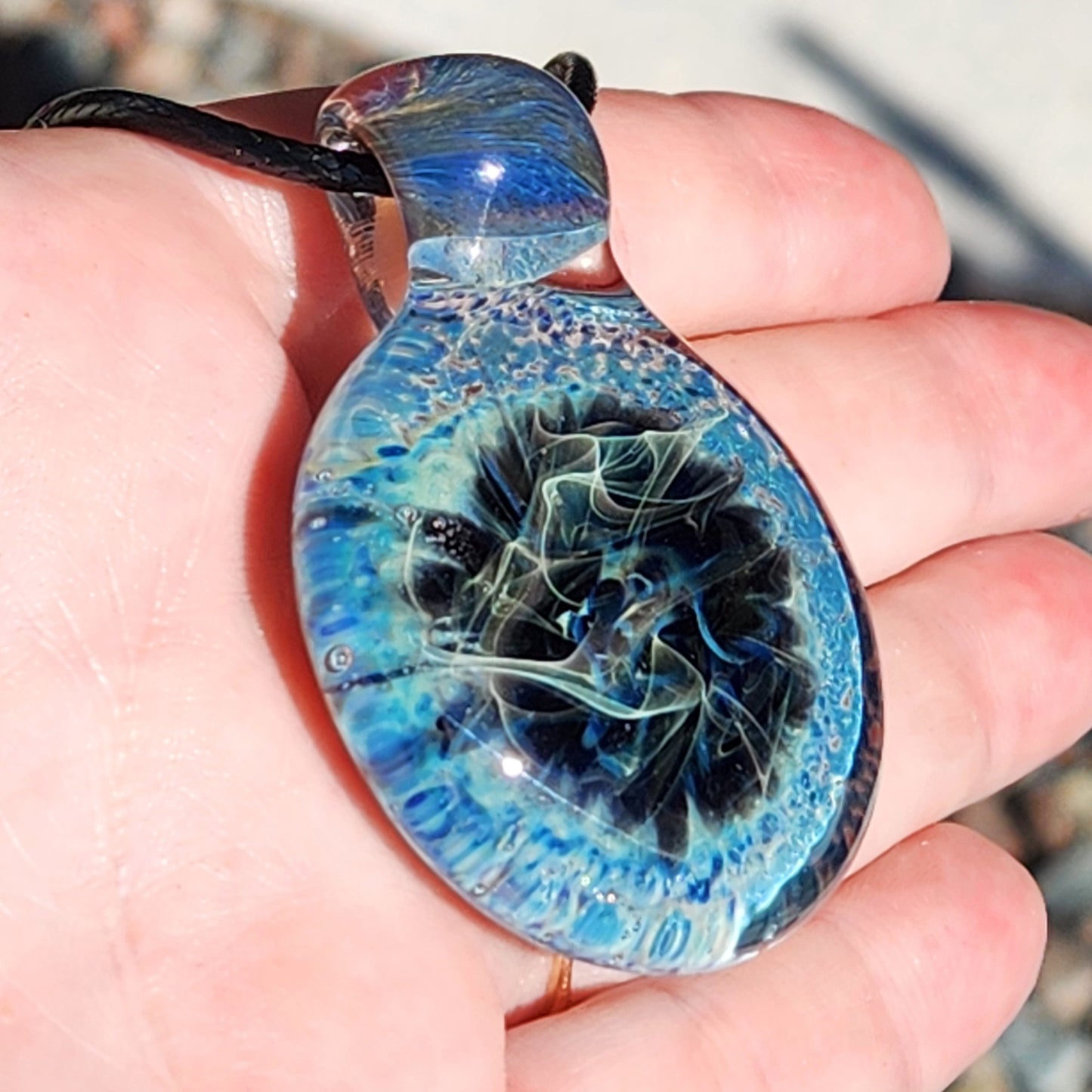 Hand holding Handmade Pendant Necklace – Winter Scene Borosilicate Glass Pendant to show scale and intricate glass details.