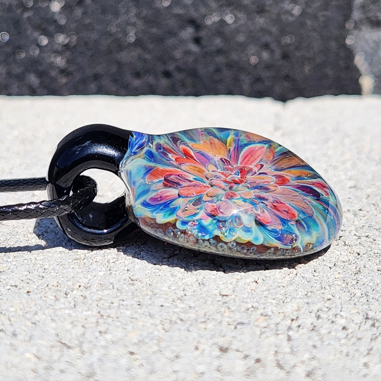 Side view of handmade blown glass pendant showing layered flower design. Unique borosilicate jewelry gift with vibrant colors.